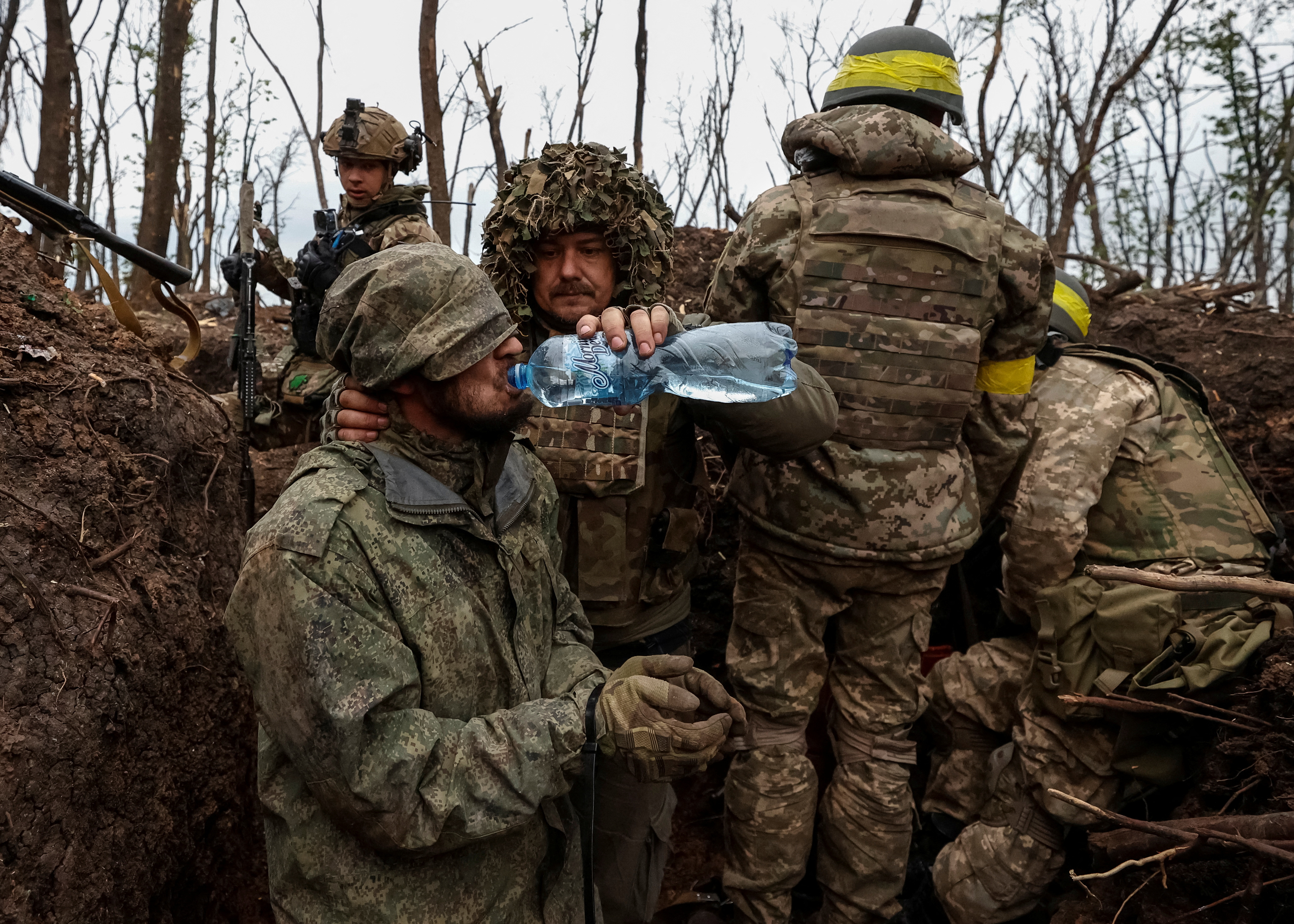 Soldados ucranianos dan agua a un prisionero de guerra ruso (via Reuters)