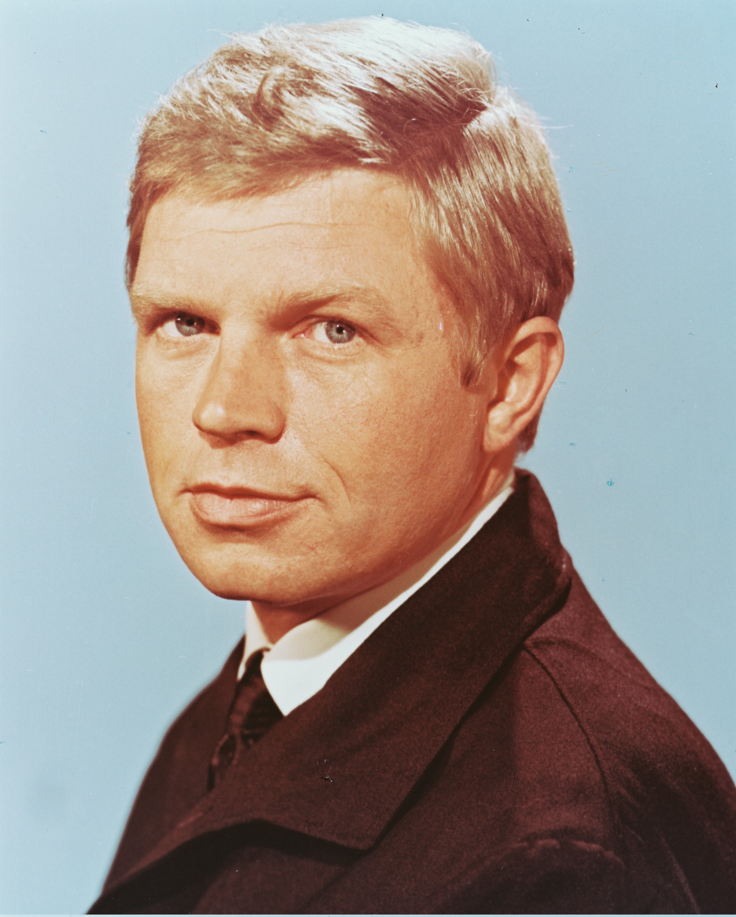 Foto de cabeza de Hardy Kruger, actor alemán, con una chaqueta marrón en un retrato de estudio, contra un fondo azul claro, alrededor de 1965. (Foto de Silver Screen Collection/Getty Images)