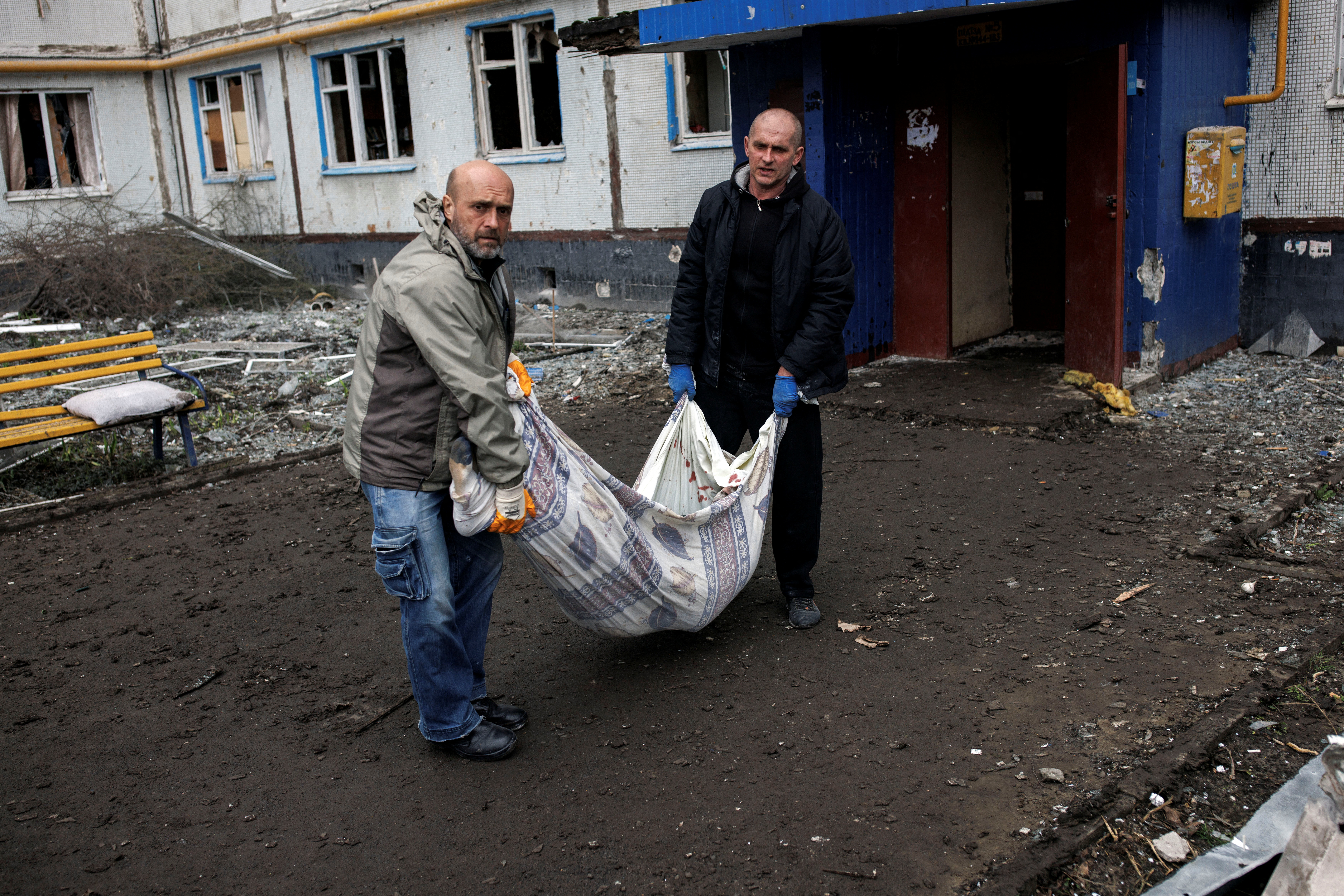 Los trabajadores de emergencia llevan el cuerpo del residente local Sergiy, de 41 años, desde su apartamento destruido, tras un ataque de artillería, en medio del ataque de Rusia a Ucrania, en Kharkiv, Ucrania, 13 de abril de 2022. REUTERS/Alkis Konstantinidis