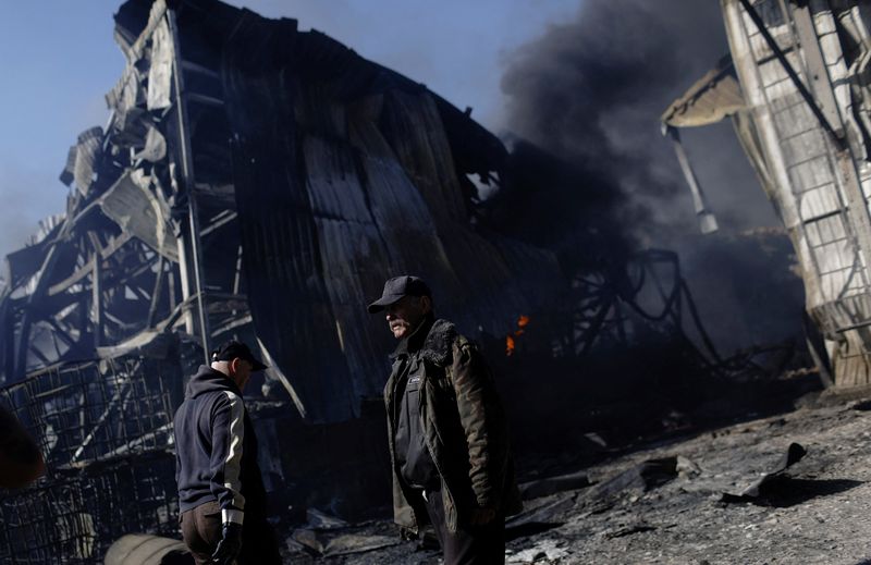 Personas caminan en un área dañada dentro de una planta en llamas, luego del bombardeo ruso en medio del ataque de Rusia contra Ucrania, en Járkov, Ucrania,