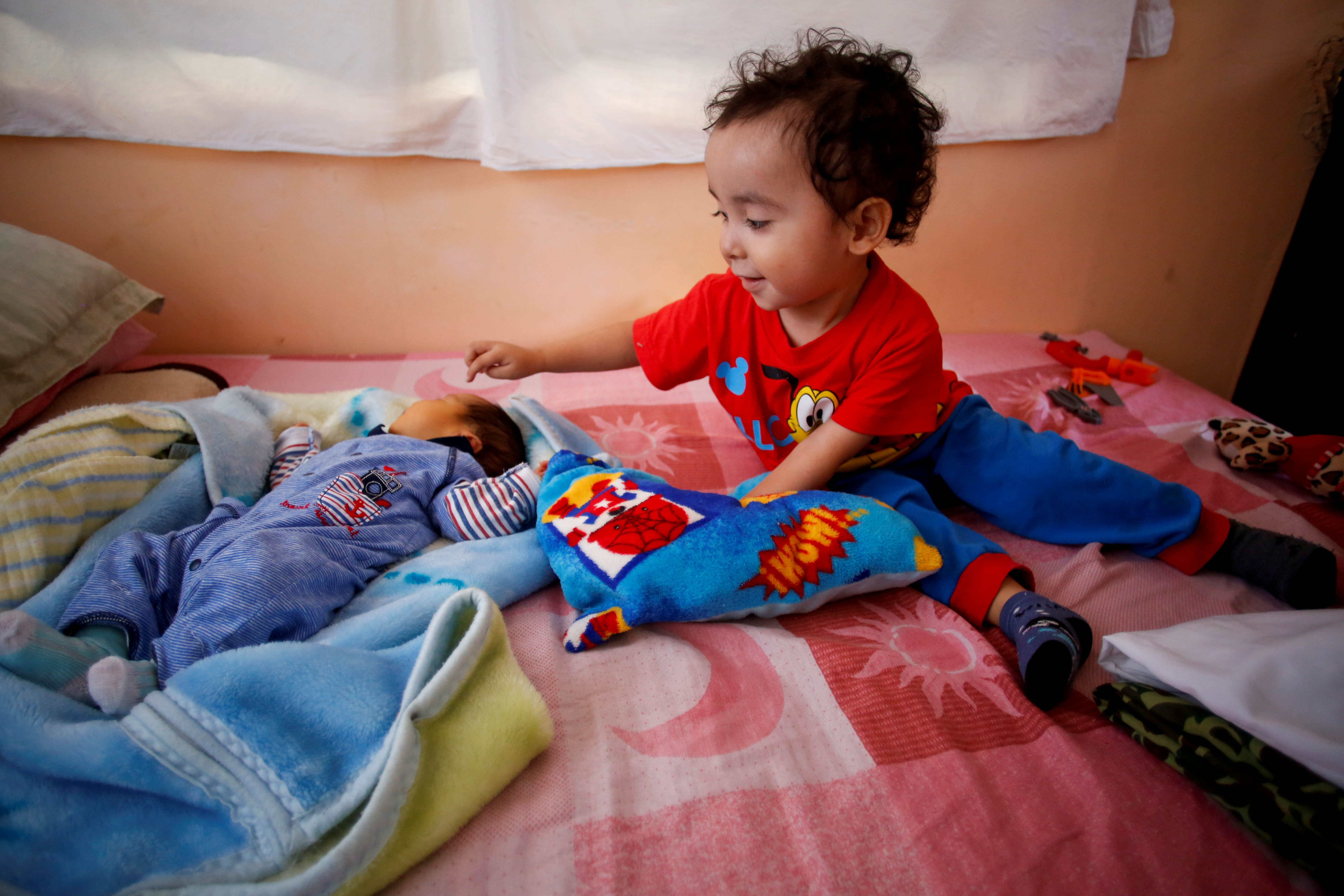 Angel Flores López, de 3 años, señala a su hermano recién nacido Sabino Yoehi Flores López mientras se sientan en una cama en el apartamento de sus abuelos, en Iztapalapa, Ciudad de México, México, 4 de junio de 2020. Foto: REUTERS / Gustavo Graf.