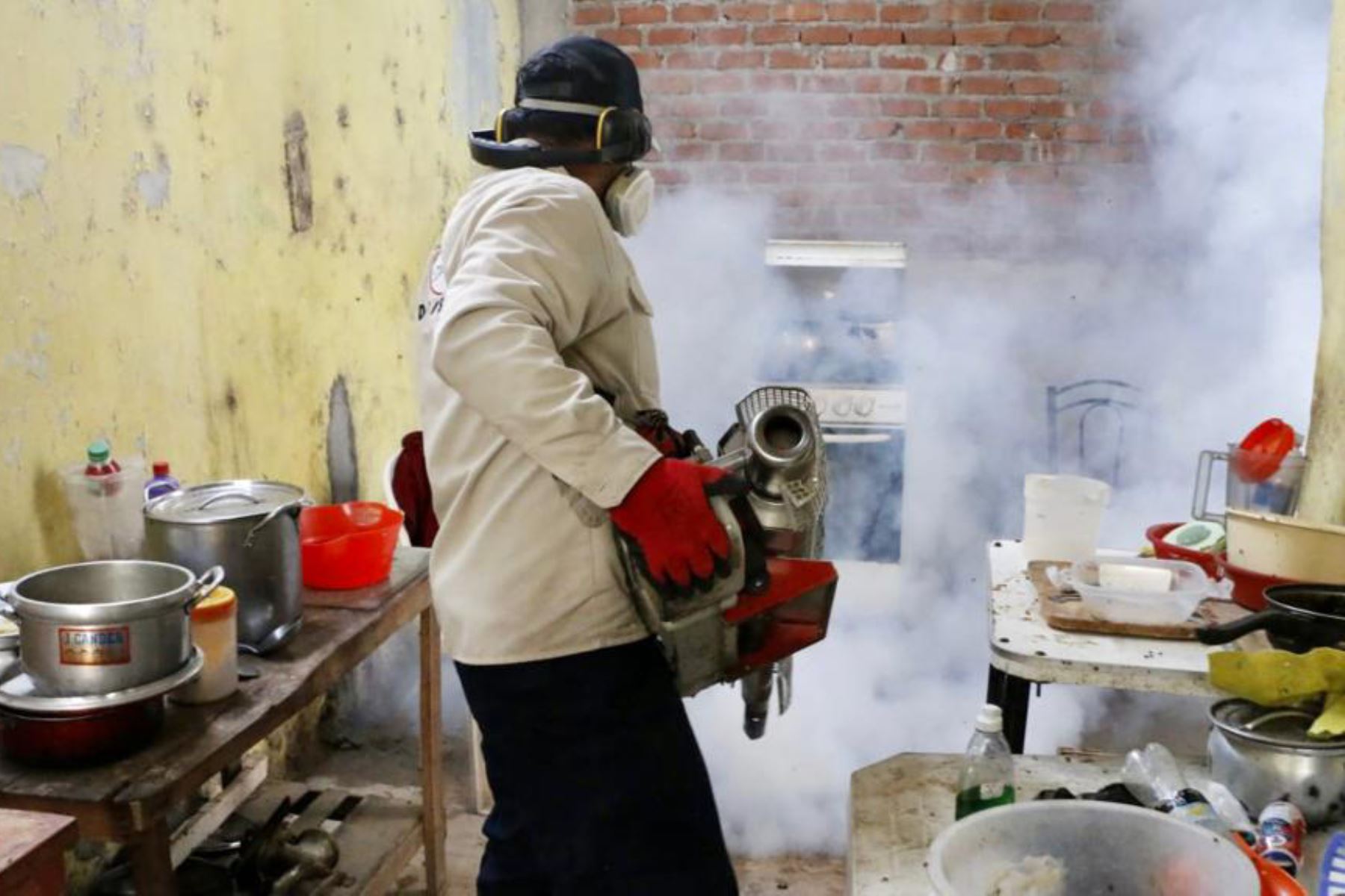 Un trabajador de salud fumiga contra los mosquitos para ayudar a mitigar la propagación del dengue en una casa de La Primavera, en Piura.