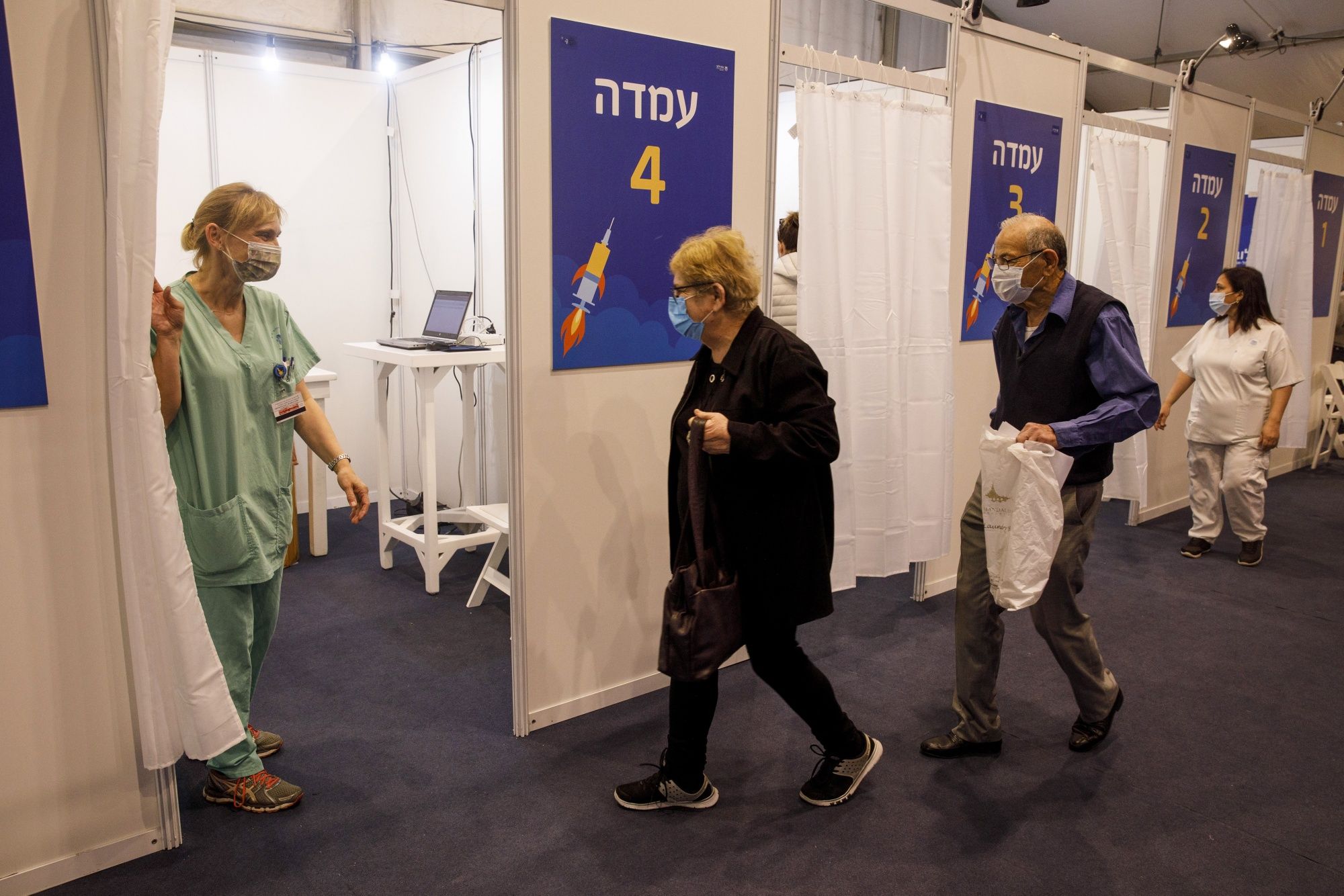 Una pareja de ancianos entra en un cubículo dentro de un centro de vacunación masiva contra el covid-19 en la Plaza Rabin en Tel Aviv, Israel, el lunes 4 de enero de 2021