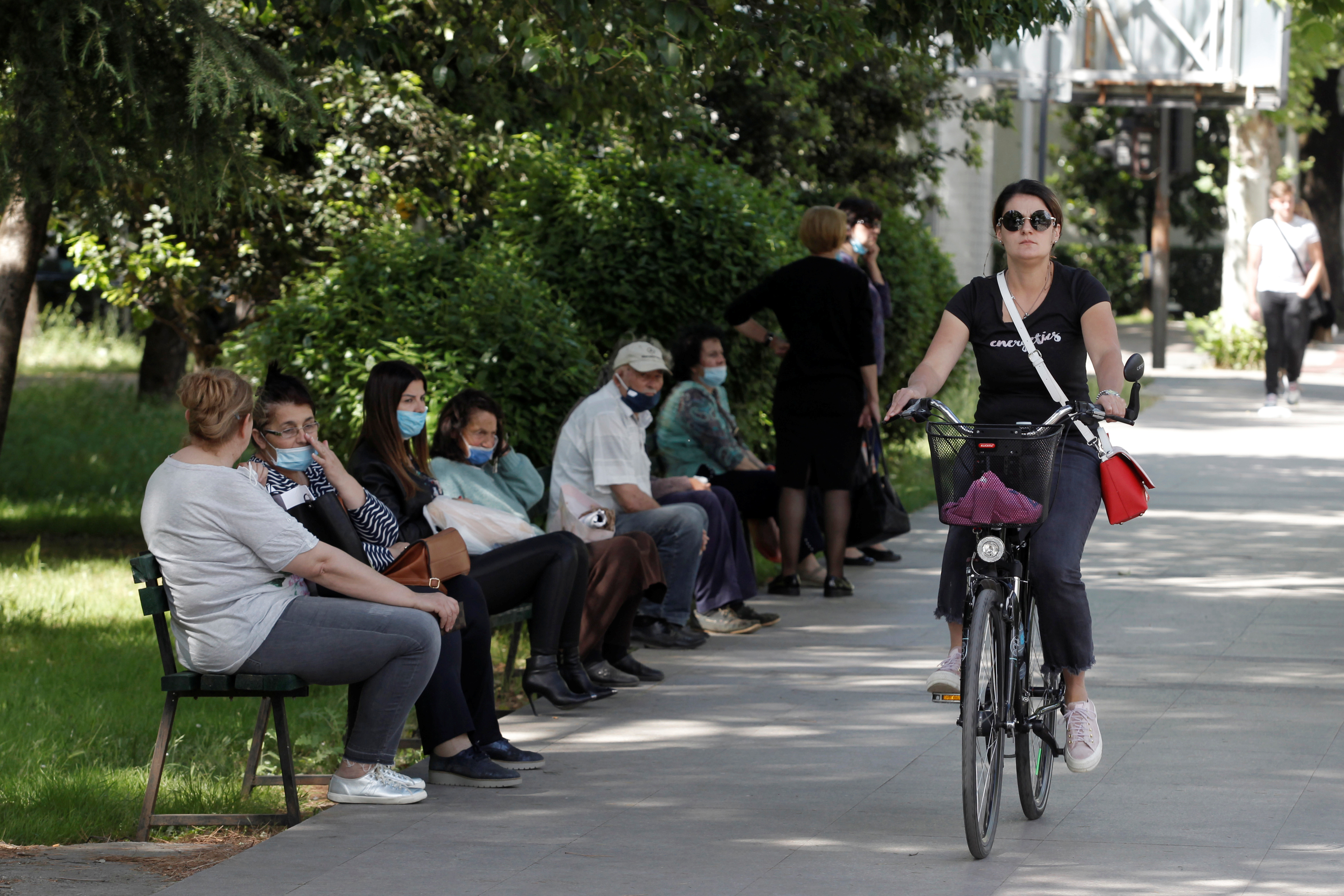 Una mujer anda en bicicleta junto a personas que esperan un autobús después de que el Primer Ministro Dusko Markovic declarara a Montenegro libre de coronavirus, el 25 de mayo de 2020. (REUTERS/Stevo Vasiljevic)
