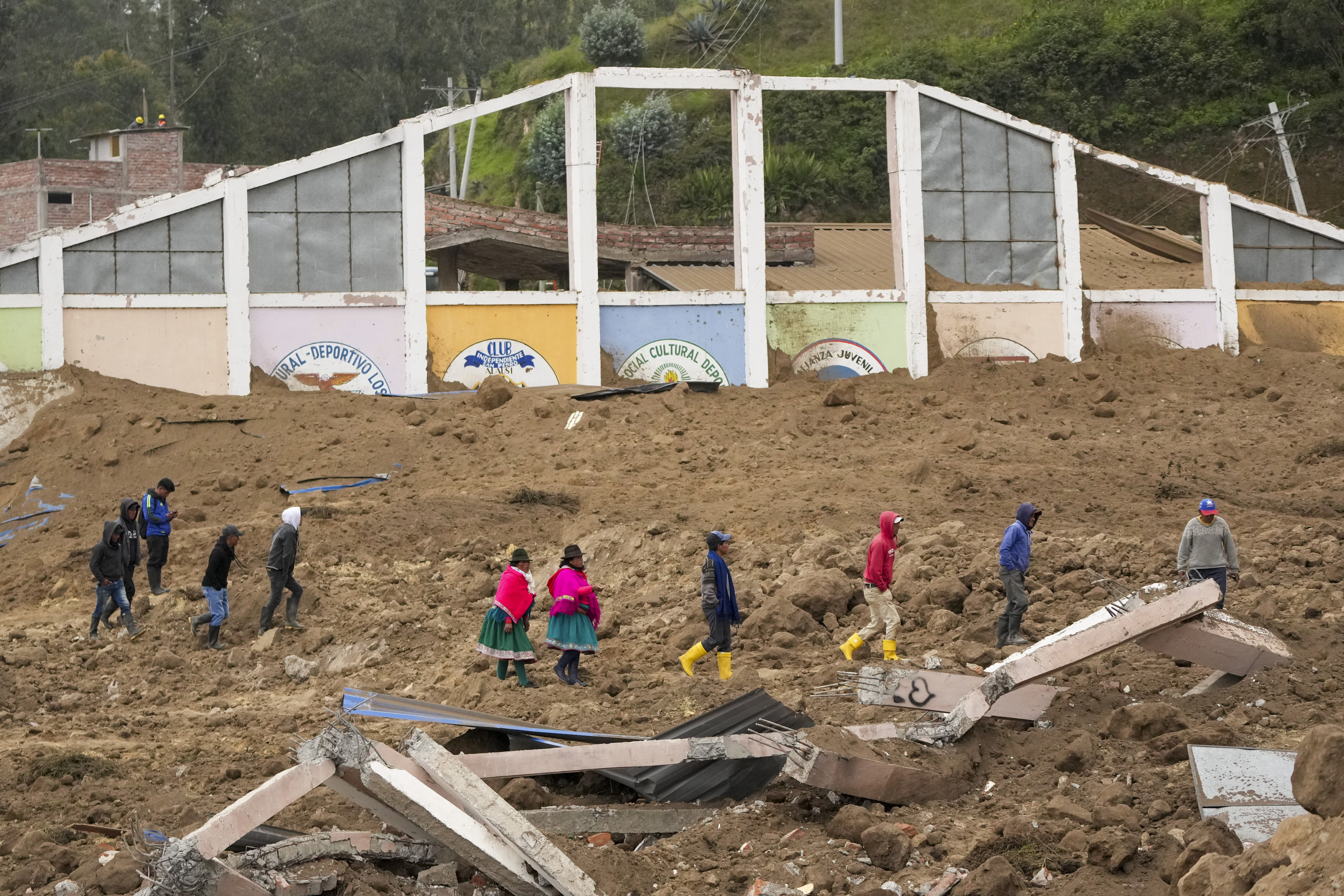 Residentes caminan entre edificios destruidos por el mortífero alud, causado por las intensas lluvias, que enterró decenas de viviendas en Alausí, Ecuador, el lunes 27 de marzo de de 2023. (AP Foto/Dolores Ochoa)