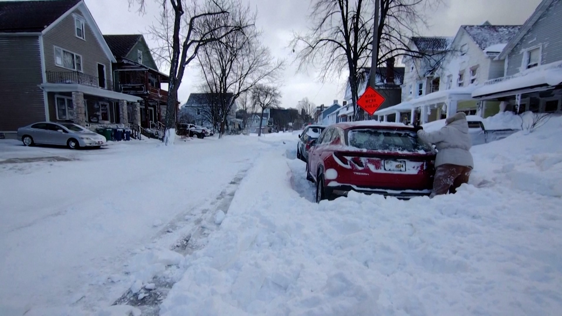 Una mujer trata de quitar la nieve que se encuentra sobre su auto. Reuters