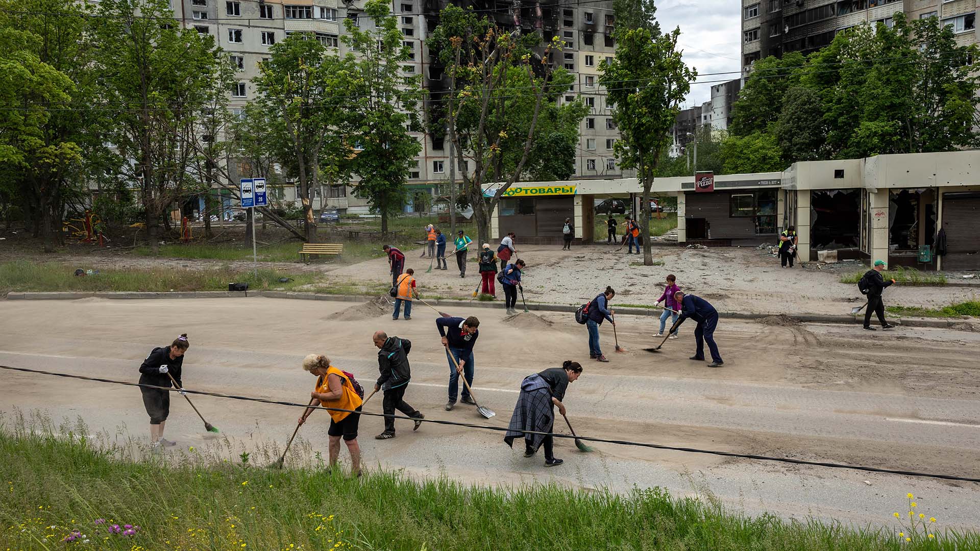 Trabajadores del transporte público barren metralla y restos de guerra en un antiguo barrio del frente el 25 de mayo de 2022 en Kharkiv, Ucrania.
