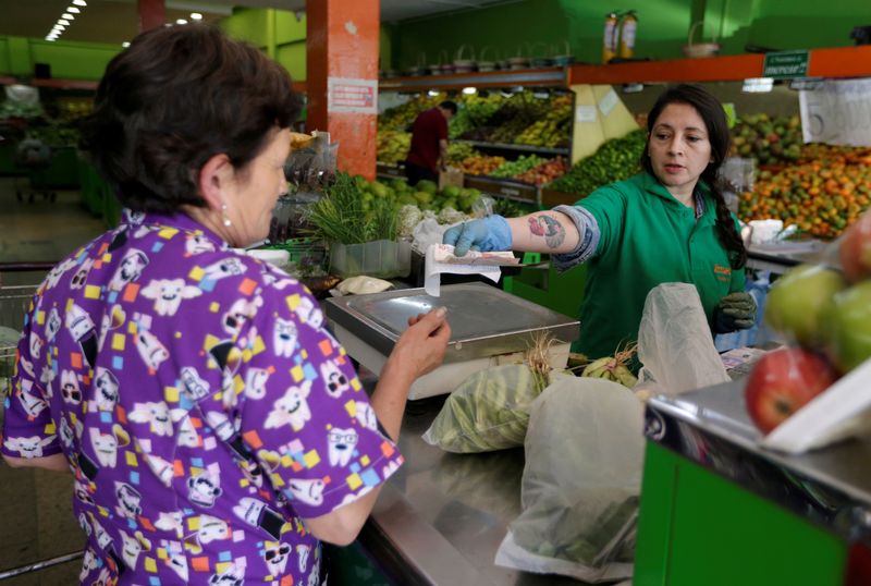 Foto de archivo. Una mujer recibe su cambio de una cajera en un supermercado en Bogotá, Colombia, 30 de octubre, 2018. REUTERS/Luisa González