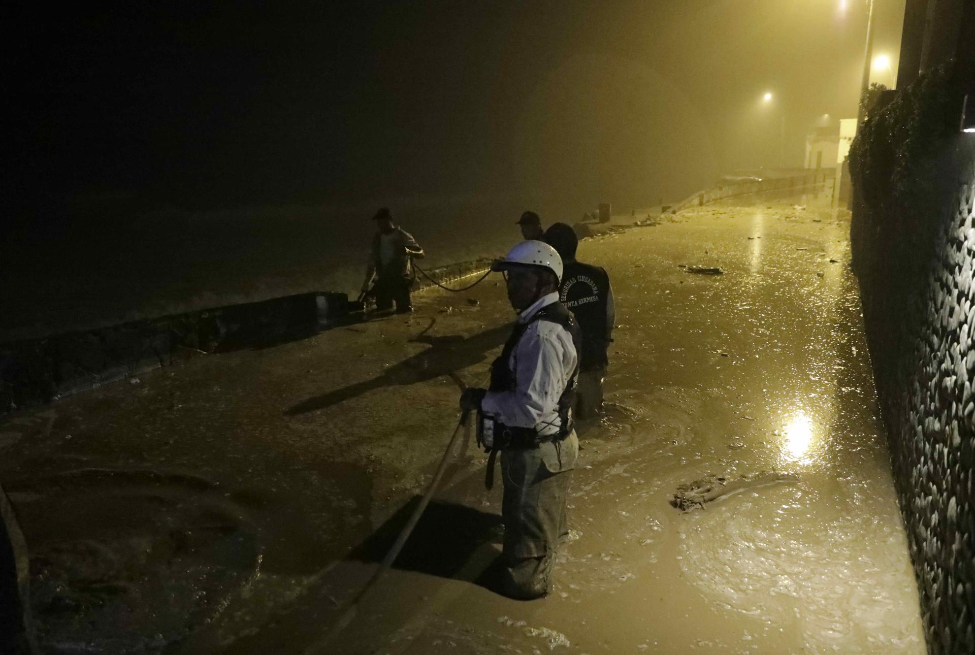 Pobladores de Punta Hermosa al sur de Lima, observan el aluvión de lodo que inundó las calles hoy en Lima.  EFE/Stringer