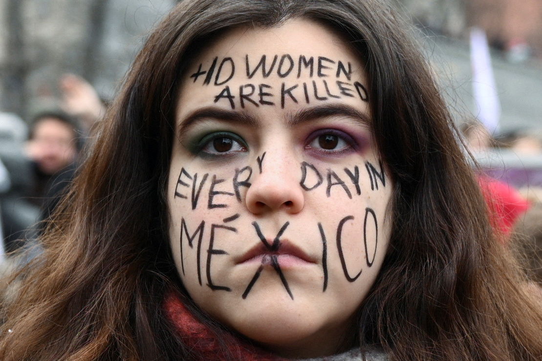 Una mujer muestra un mensaje en su cara, "+10 mujeres son asesinadas todos los días en Mexico", en la marcha por el 8M en Alemania. 