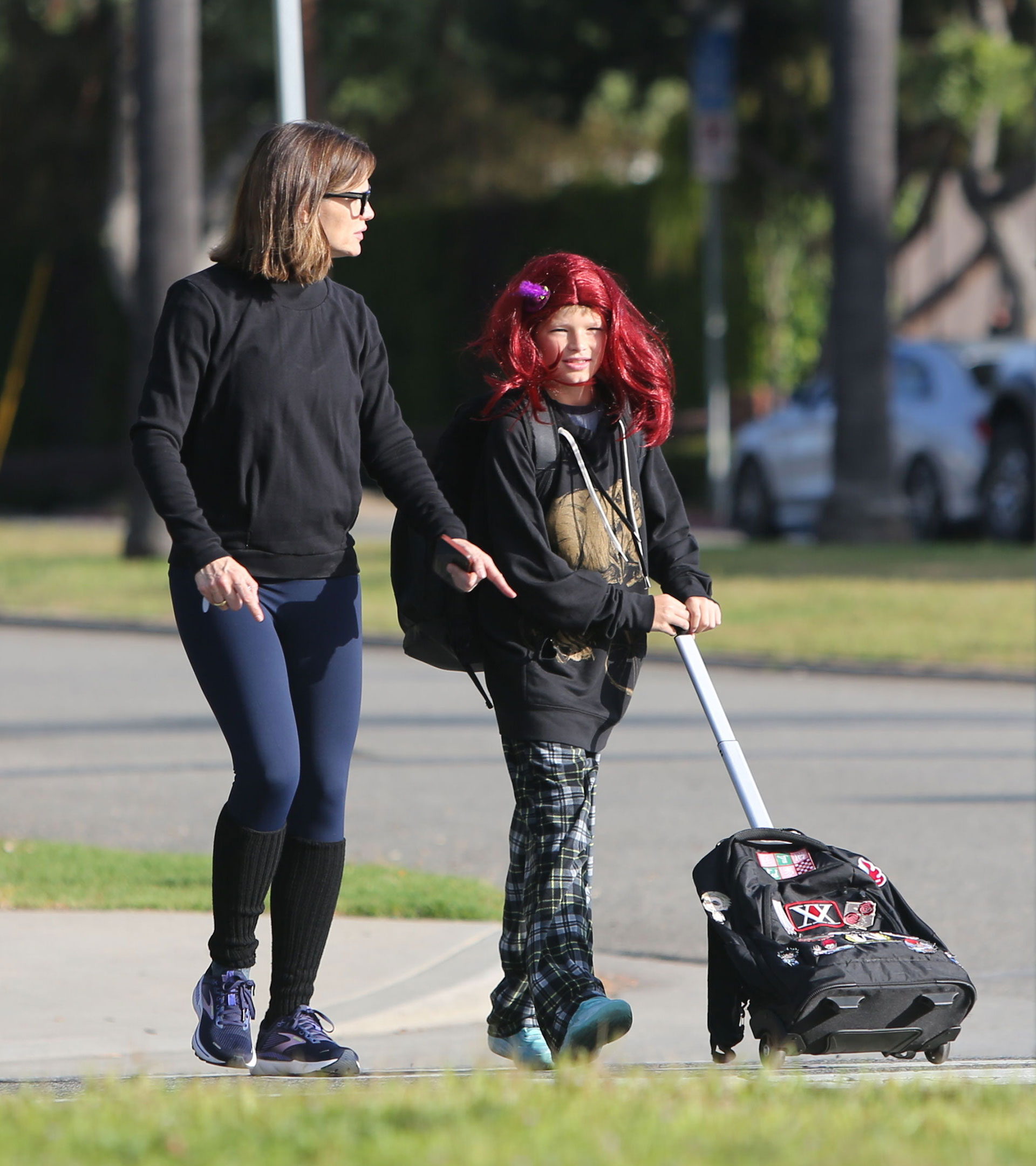Jennifer Garner llevó a su hijo Samuel, de 10 años, al colegio en Santa Mónica. El niño llevó una peluca color roja, cargó una mochila y también una valija con ruedas. Ella, luego aprovechó la oportunidad para ir al gimnasio. Para ello, llevó un conjunto deportivo de calzas largas azules, polainas negras que combinó con su buzo polar