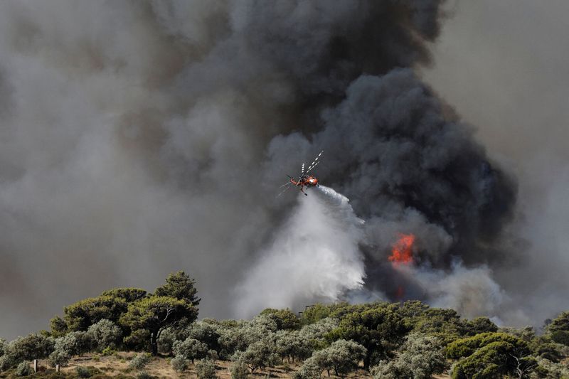 Un helicóptero de extinción de incendios realiza una descarga de agua mientras en un incendio del suburbio de Pikermi en Atenas, Grecia, 20 de julio de 2022. REUTERS/Louiza Vradi