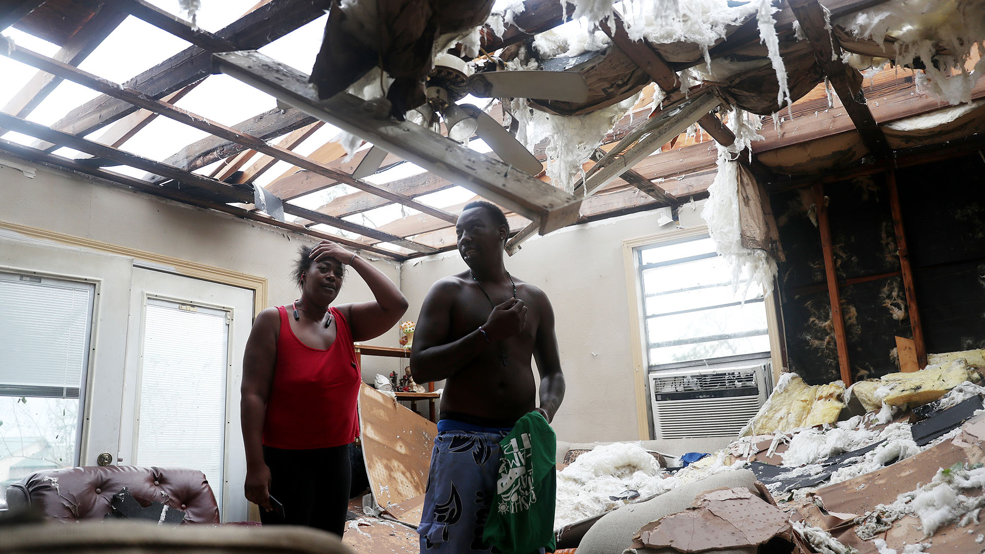 Latasha Myles y Howard Anderson están de pie en su sala de estar, donde estaban sentados cuando el techo se voló alrededor de las 2:30 am cuando el huracán Laura pasó por la zona en Lake Charles, Louisiana (Joe Raedle/Getty Images/AFP)