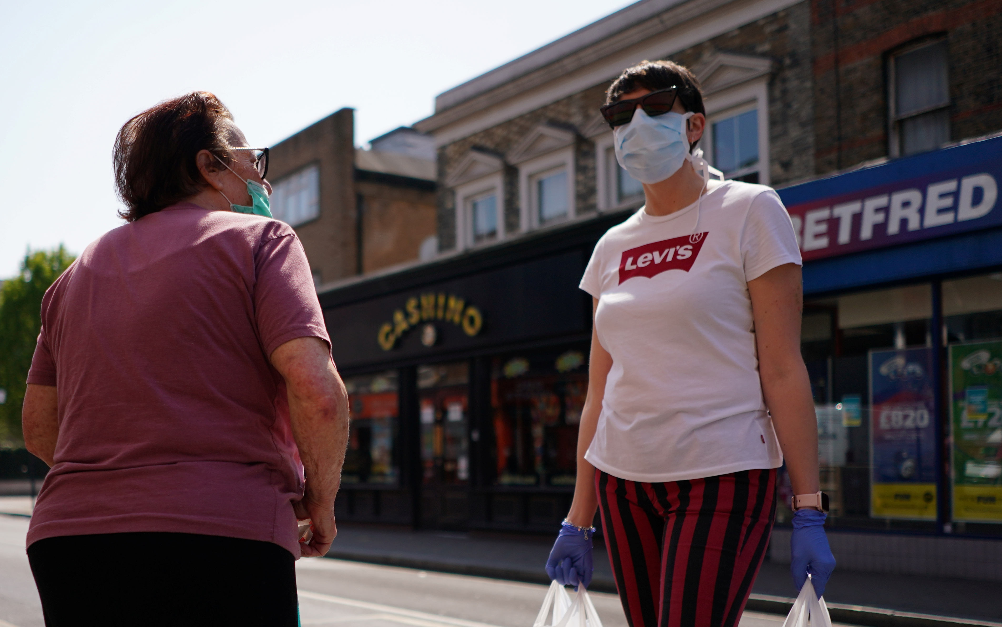 Women wearing face masks speak to eachother, as the spread of the coronavirus disease (COVID-19) continues, at North End Road in London, Britain, April 24, 2020. REUTERS/Henry Nicholls