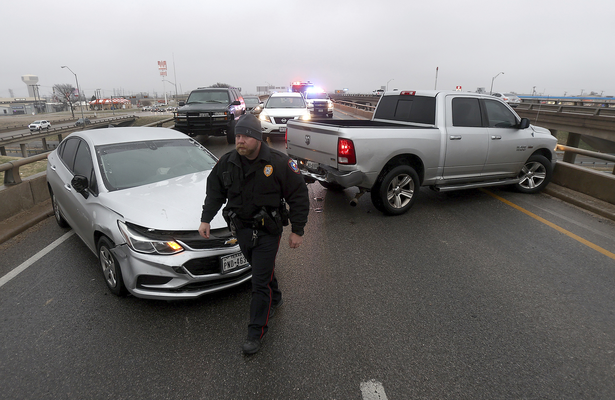Un policía de Waco trabaja en el sitio de un accidente de cuatro vehículos, el martes 31 de enero de 2023, en una carretera de Waco, Texas. (Jerry Larson/Waco Tribune-Herald vía AP)