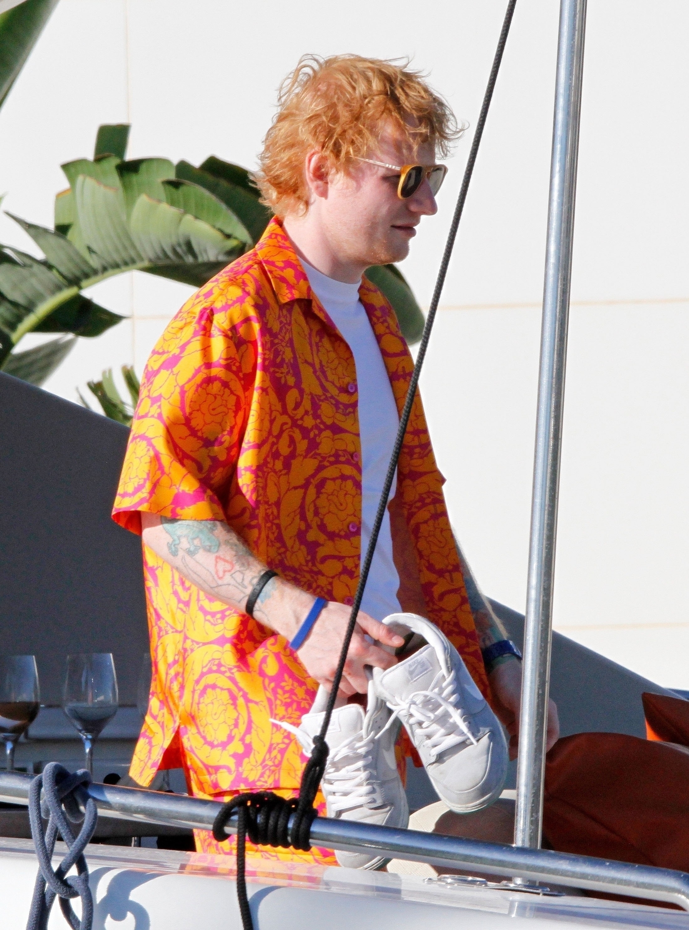 El cantante británico Ed Sheeran disfruta de unos días de descanso en Ibiza, donde se lo fotografió en un barco y con un atuendo muy particular:  un conjunto de pantalón y remara Versace amarillo y naranja