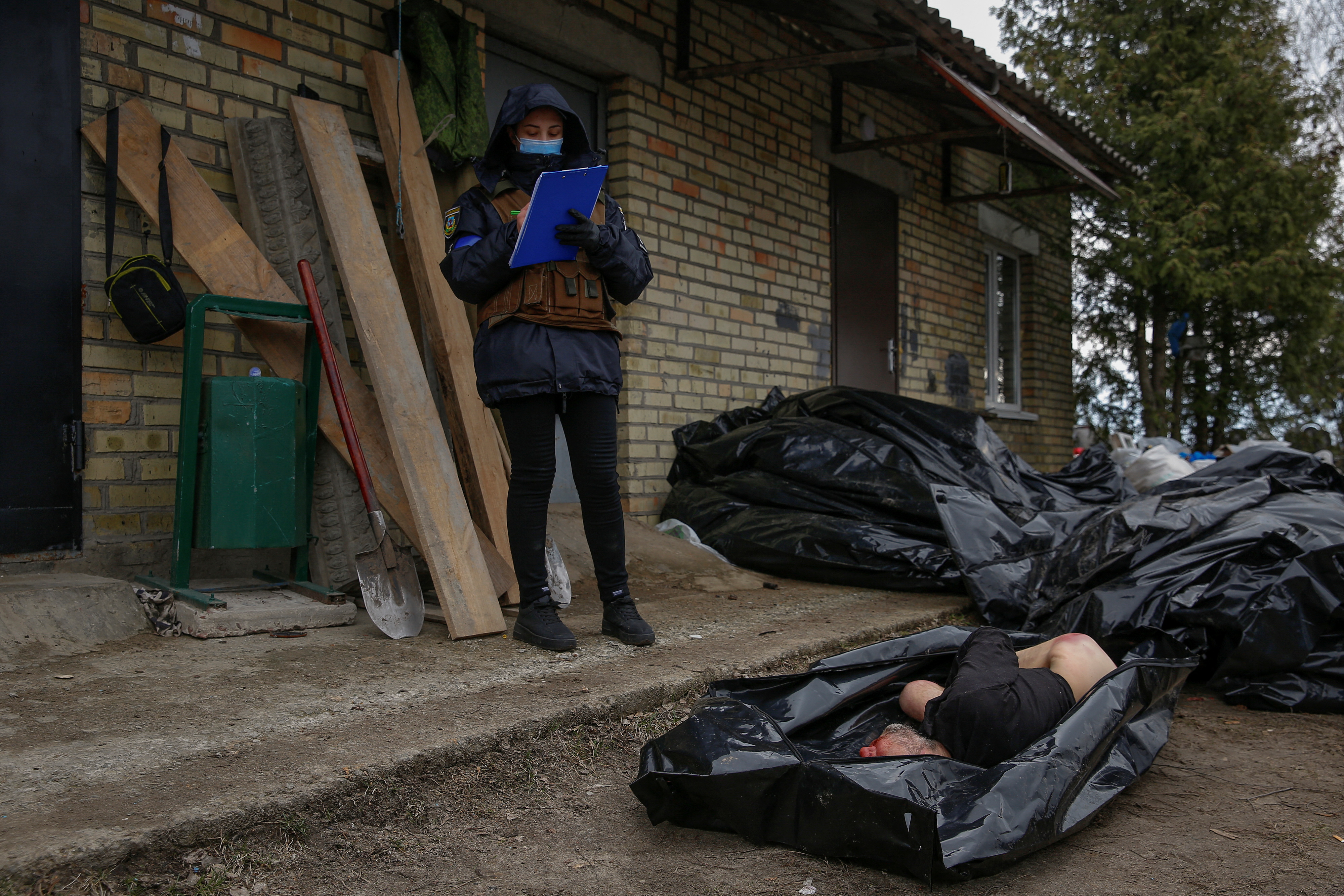 Un policía toma notas mientras examina los cuerpos de civiles asesinados que fueron hallados en Bucha, presuntamente a causa de disparos de las fuerzas rusas que ocuparon la ciudad. REUTERS/Oleg Pereverzev