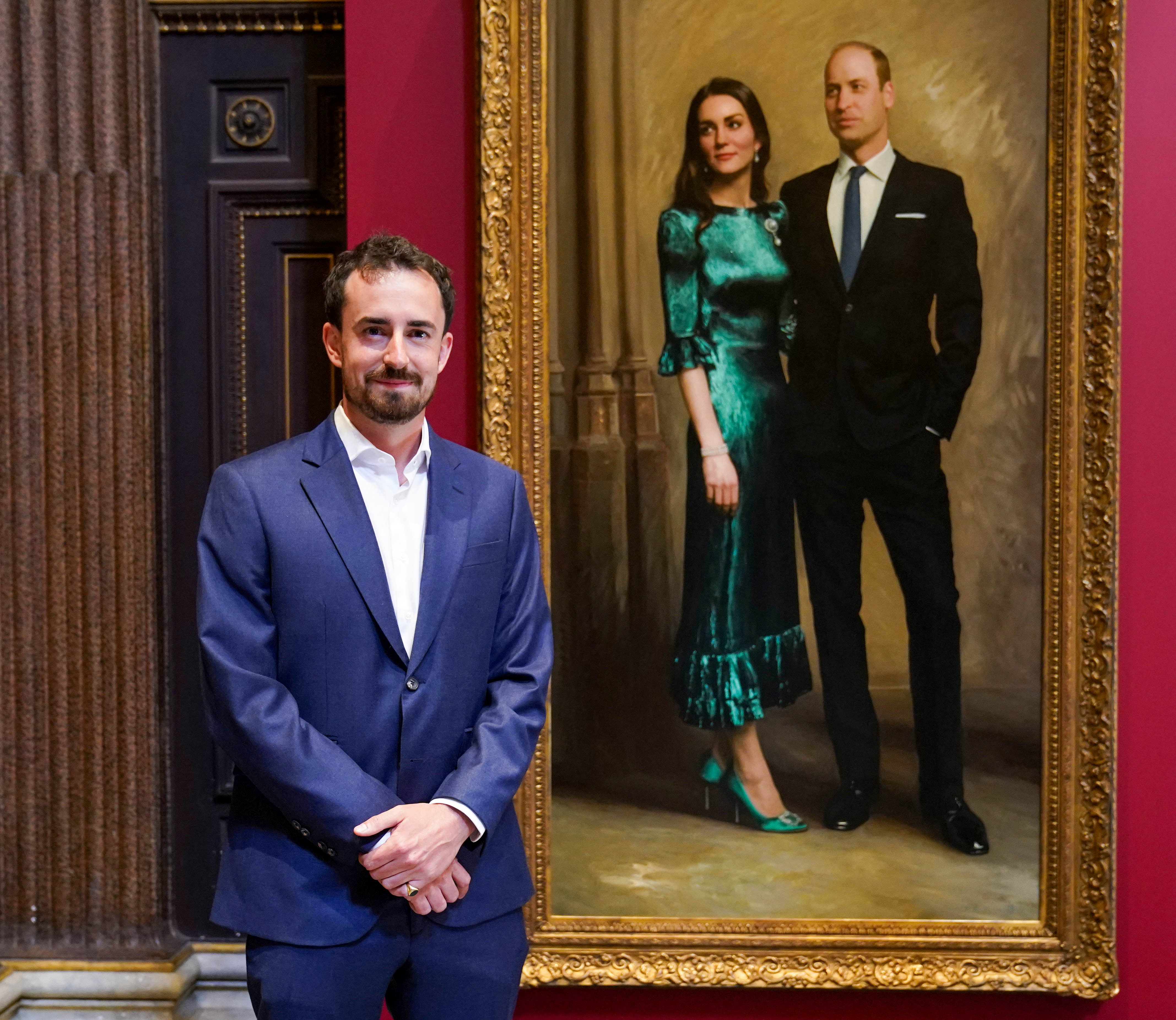 El artista Jamie Coreth posa frente a la pintura de la pareja real pintada por él, en el Museo Fitzwilliam en Cambridge, Gran Bretaña, el 23 de junio de 2022 (REUTERS)