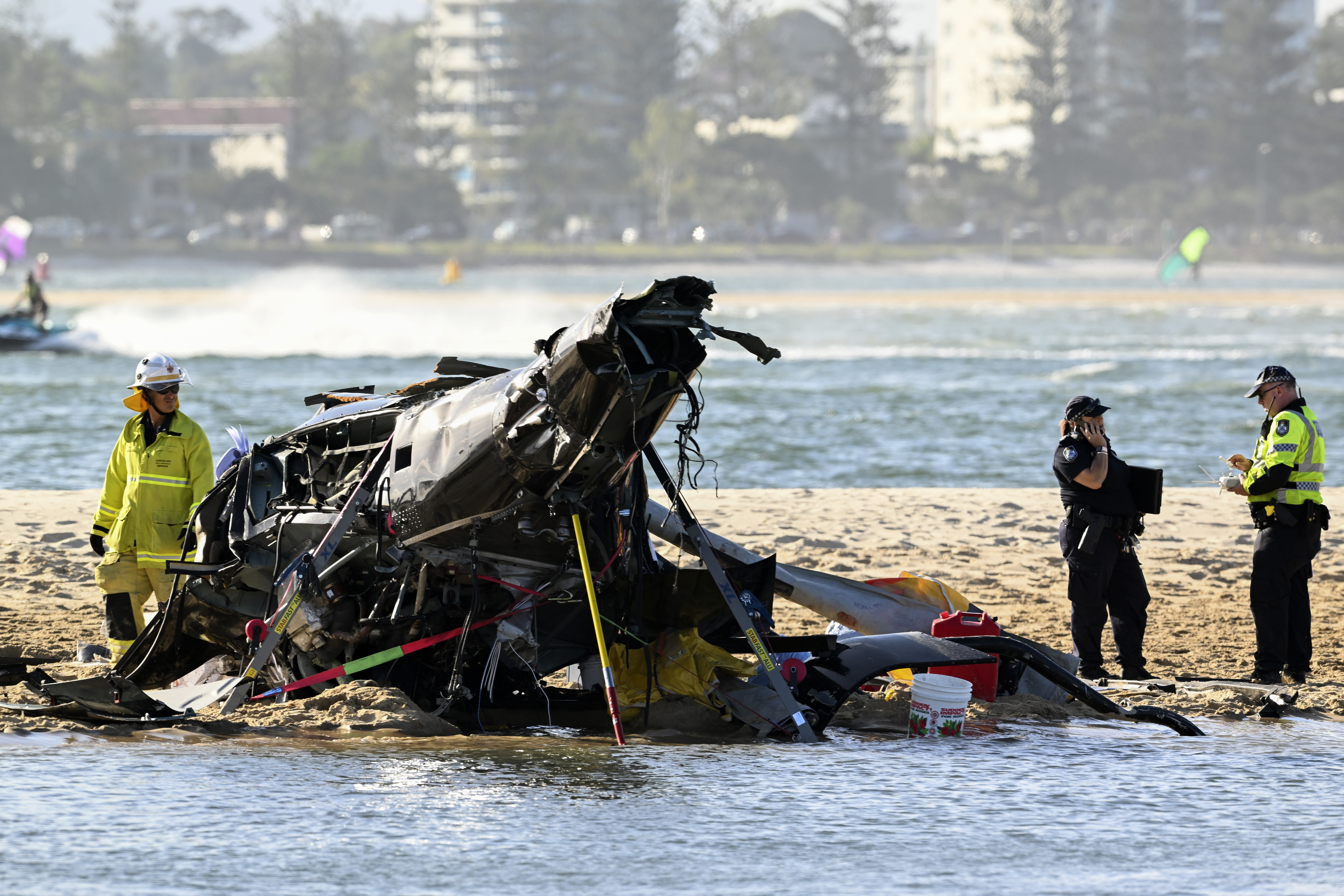 Los trabajadores de emergencia inspeccionan un helicóptero en una escena de colisión cerca de Seaworld, en Gold Coast, Australia. (Imagen de Dave Hunt/AAP vía AP)

