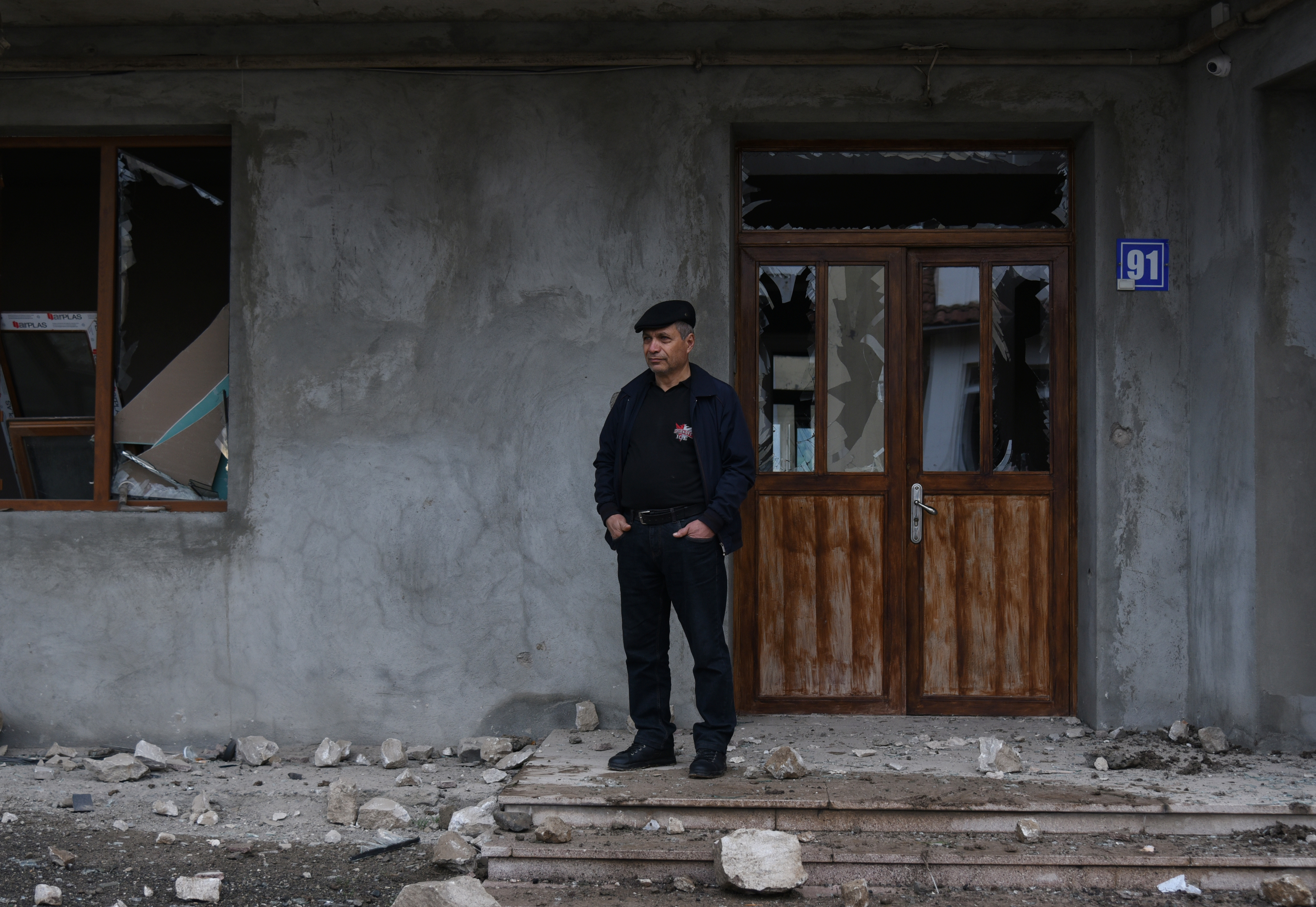 A local resident stands next to a building damaged by recent shelling during a military conflict over the breakaway region of Nagorno-Karabakh, in Stepanakert October 8, 2020. David Ghahramanyan/NKR InfoCenter/PAN Photo/Handout via REUTERS ATTENTION EDITORS - THIS IMAGE HAS BEEN SUPPLIED BY A THIRD PARTY. MANDATORY CREDIT.