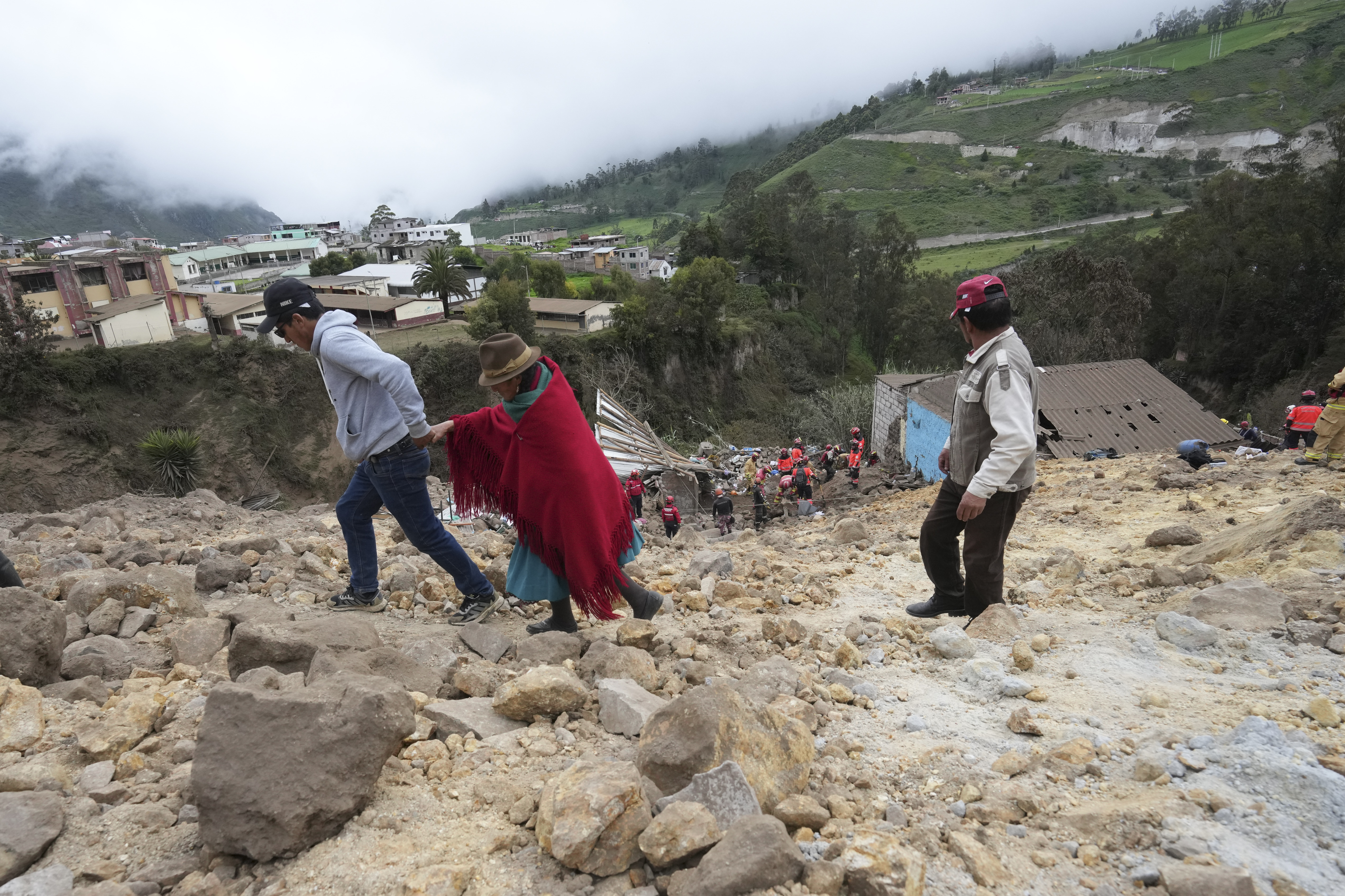 Residentes caminan entre el barro y las piedras que dejó un mortífero alud, causado por las intensas lluvias, que enterró decenas de viviendas en Alausí, Ecuador, el lunes 27 de marzo de de 2023. (AP Foto/Dolores Ochoa)