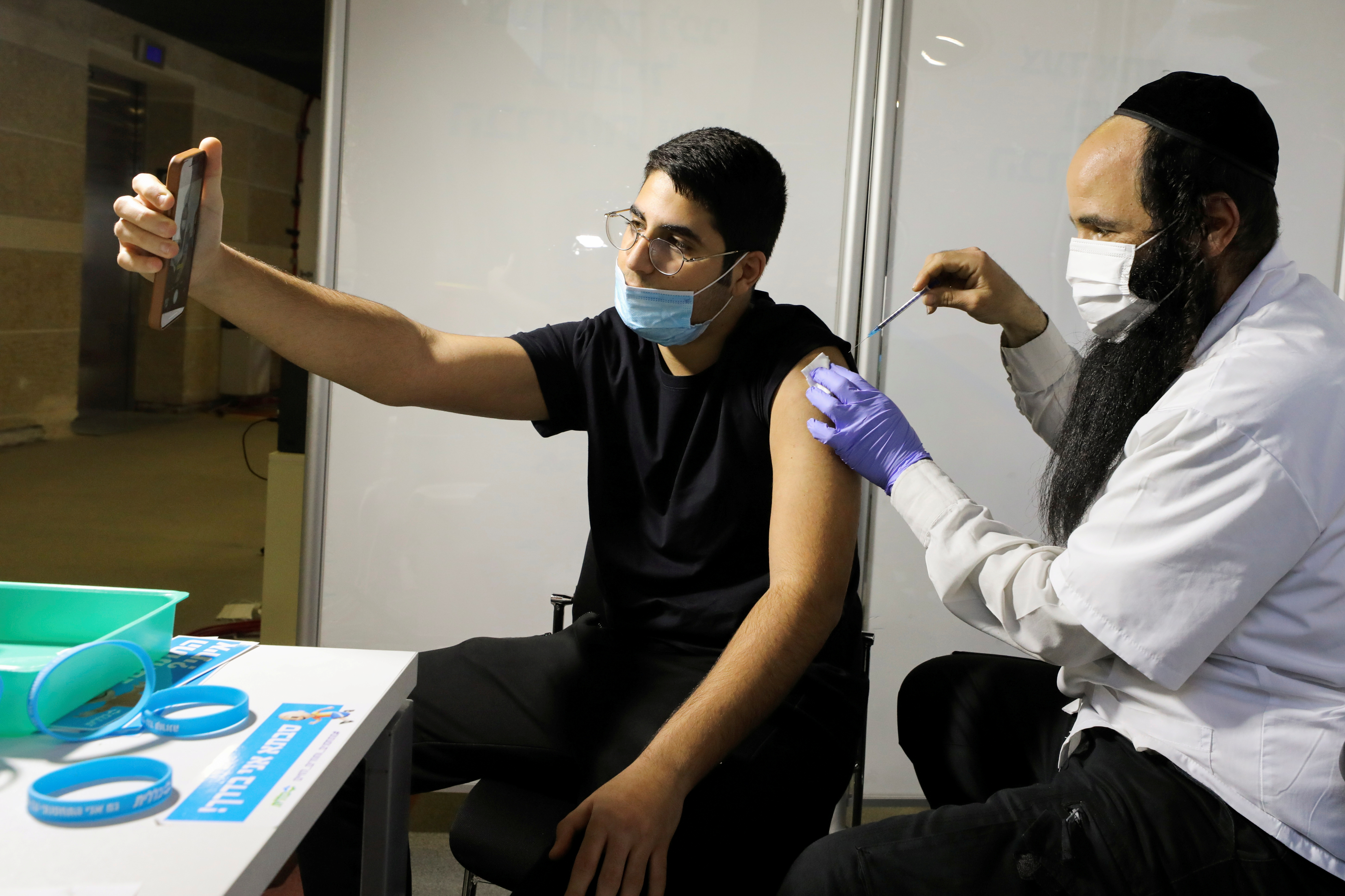 Un hombre recibe una vacuna contra la enfermedad del coronavirus (COVID-19) en un centro de vacunación temporal de la organización de mantenimiento de la salud (HMO) de Clalit, en un estadio deportivo en Jerusalén (REUTERS / Ammar Awad)

