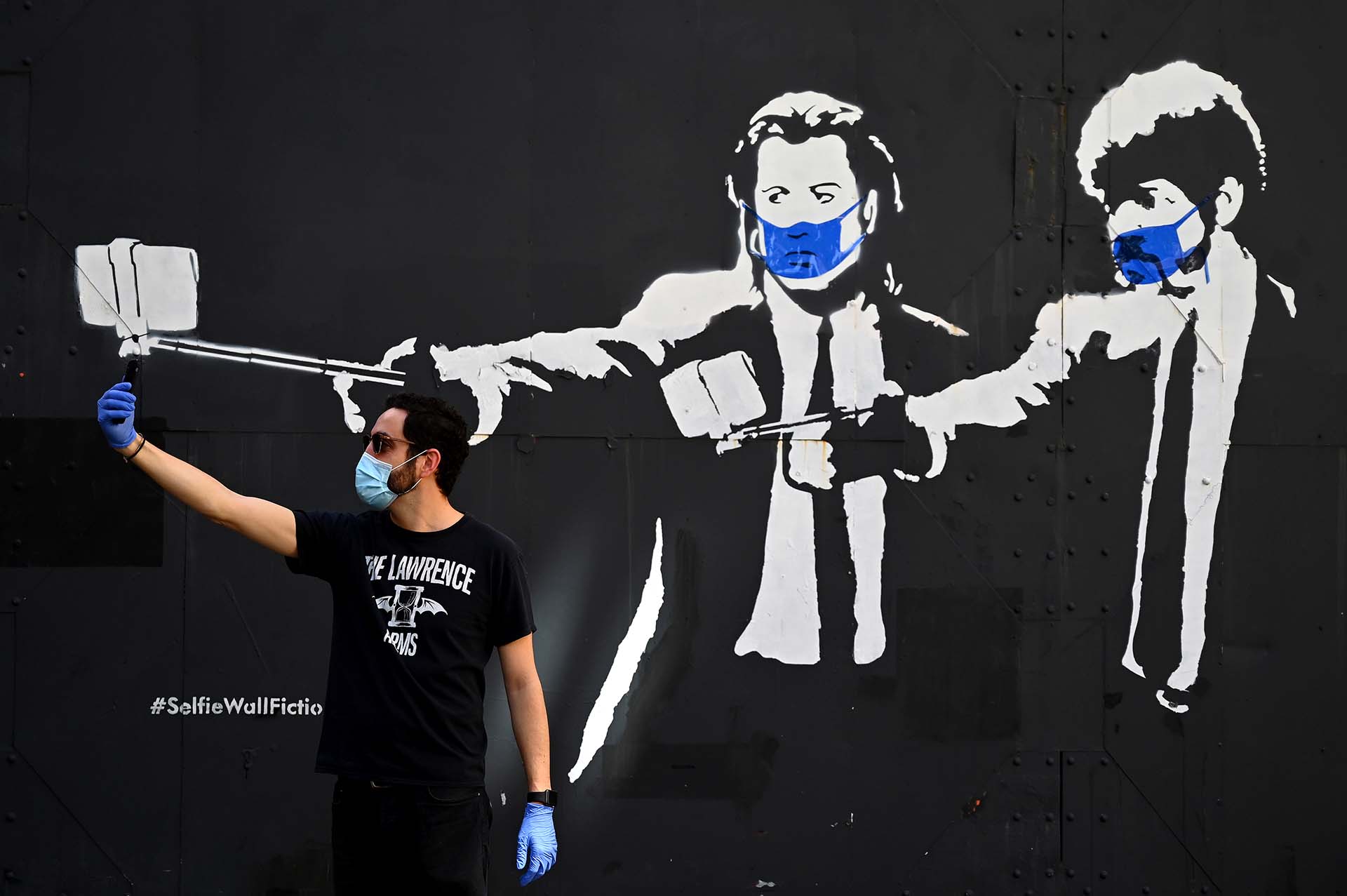 Un hombre se toma una selfie junto a un stencil de los actores Samuel L. Jackson y John Travolta en la películas