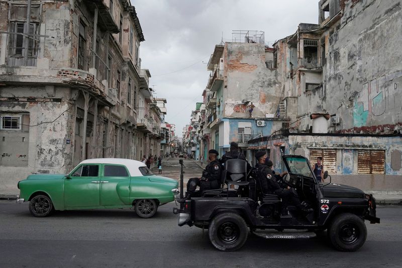 Un vehículo de las fuerzas especiales pasa junto a un coche de época en el centro de La Habana, Cuba (REUTERS/Alexandre Meneghini)