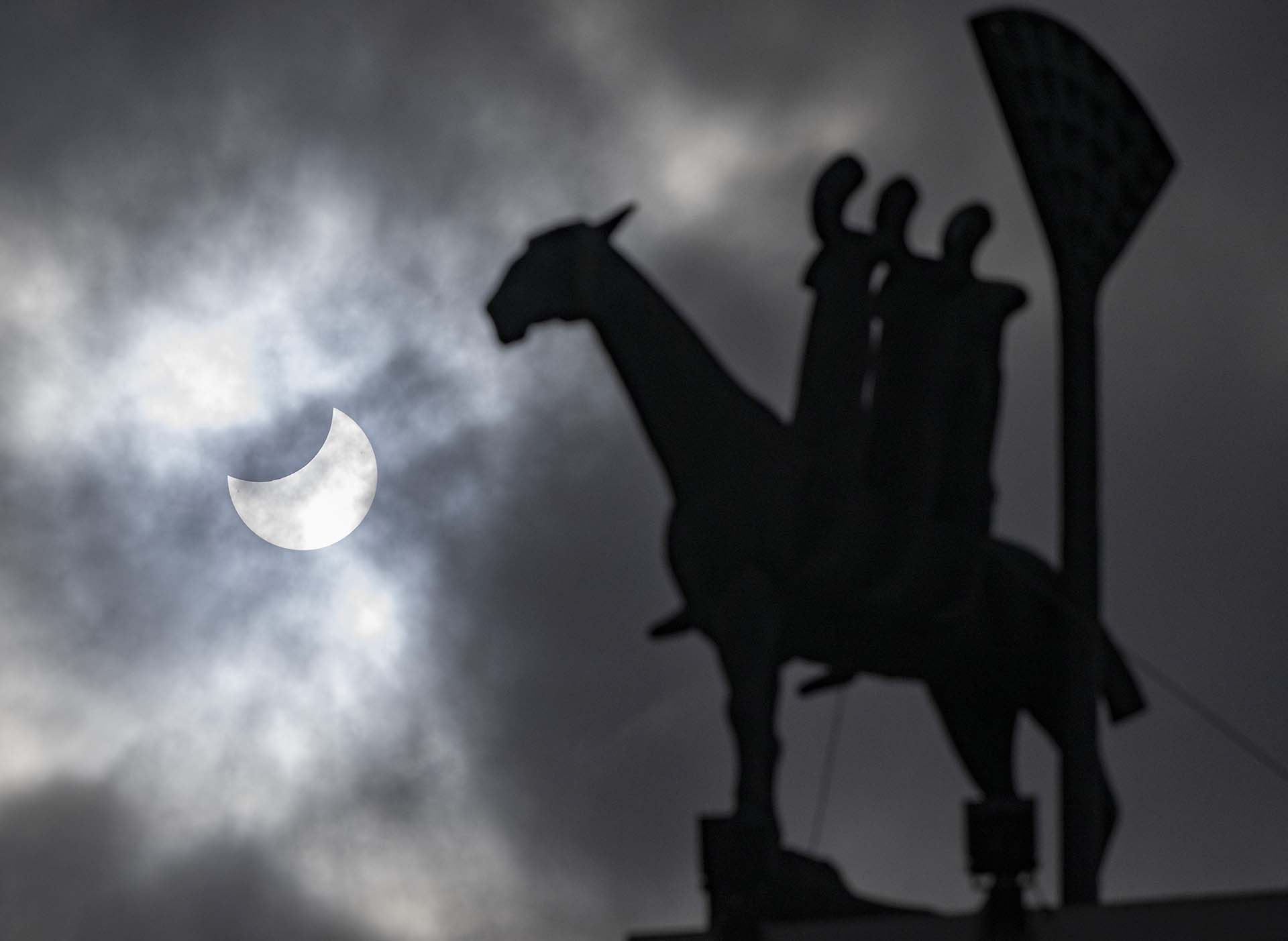 Un eclipse solar parcial (L) y la estatua "Jinete del Apocalipsis" del artista danés Bjorn Norgaard en el centro de Malmo, Suecia (Photo by Johan NILSSON / TT News Agency / AFP)