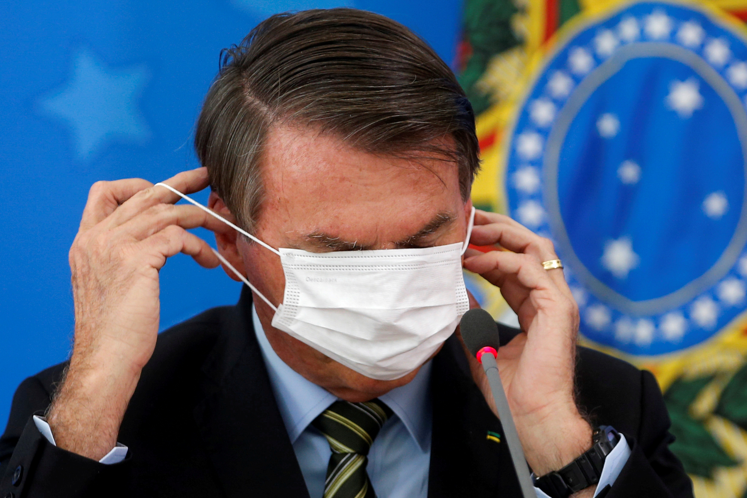 El 18 de marzo, con cierto fastidio, el presidente Jair Bolsonaro se ajusta su máscara facial durante una conferencia de prensa en la que se anunciaron las primeras medidas contra la pandemia del coronavirus en Brasil (REUTERS/Adriano Machado)