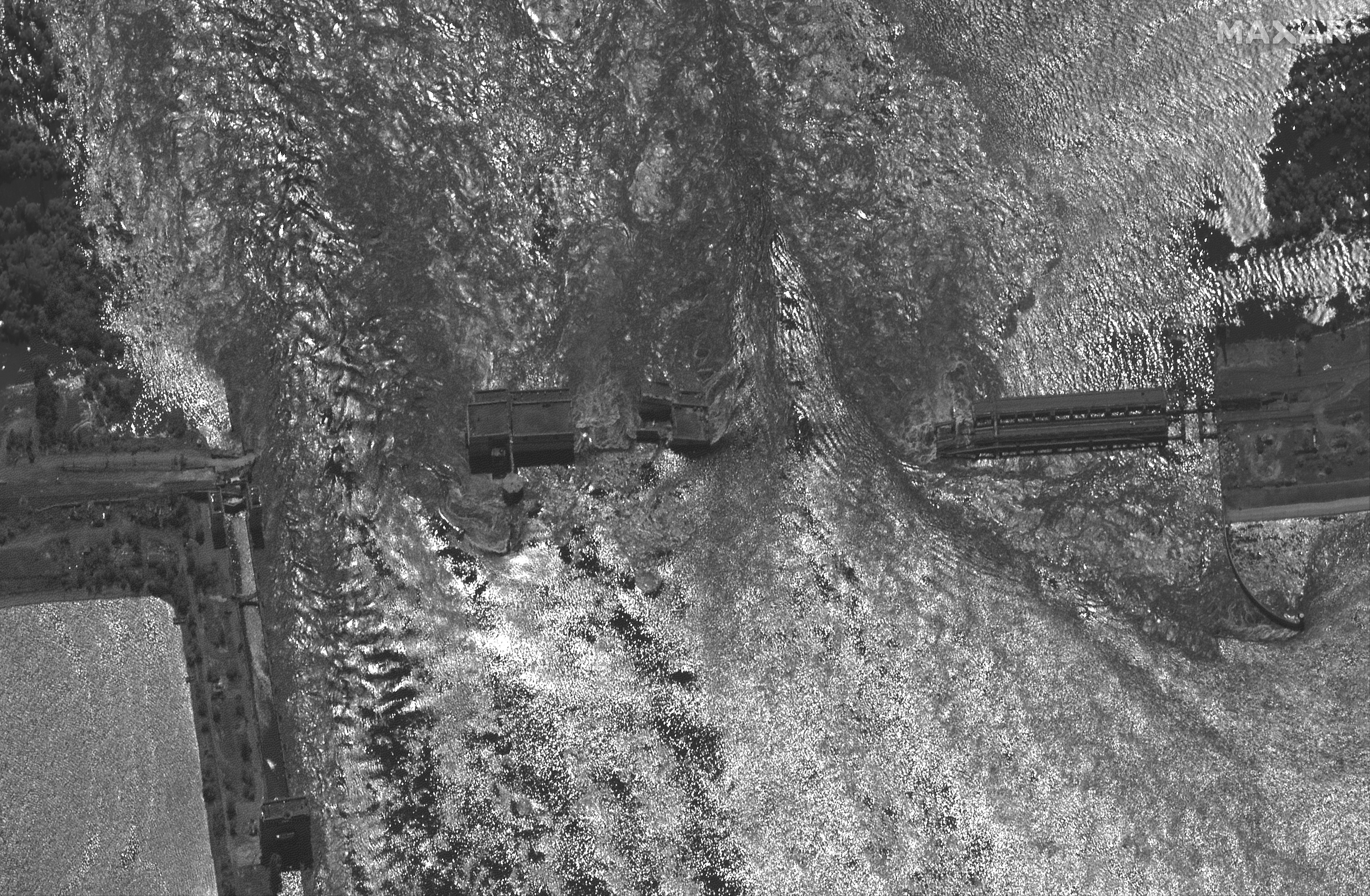 Esta imagen por satélite del 6 de uunio proporcionada por Maxar Technologies muestra la dramática diferencia con el día anterior y se aprecian los daños en el dique arrasado por el agua (Maxar Technologies via AP)