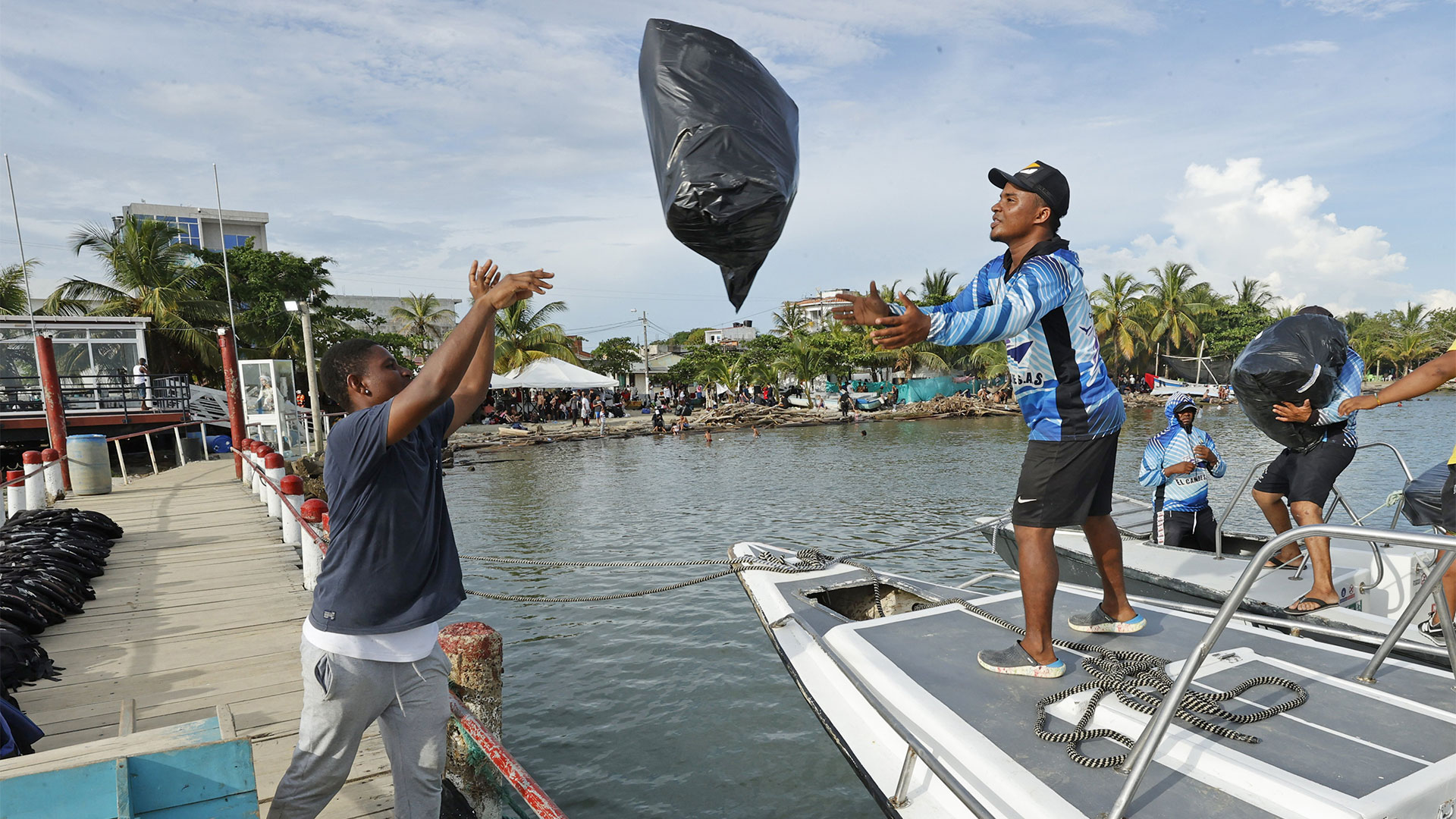 Trabajadores cargan las pertenencias de migrantes que abordarán una lancha hacia la frontera con Panamá (EFE/ Mauricio Dueñas Castañeda)