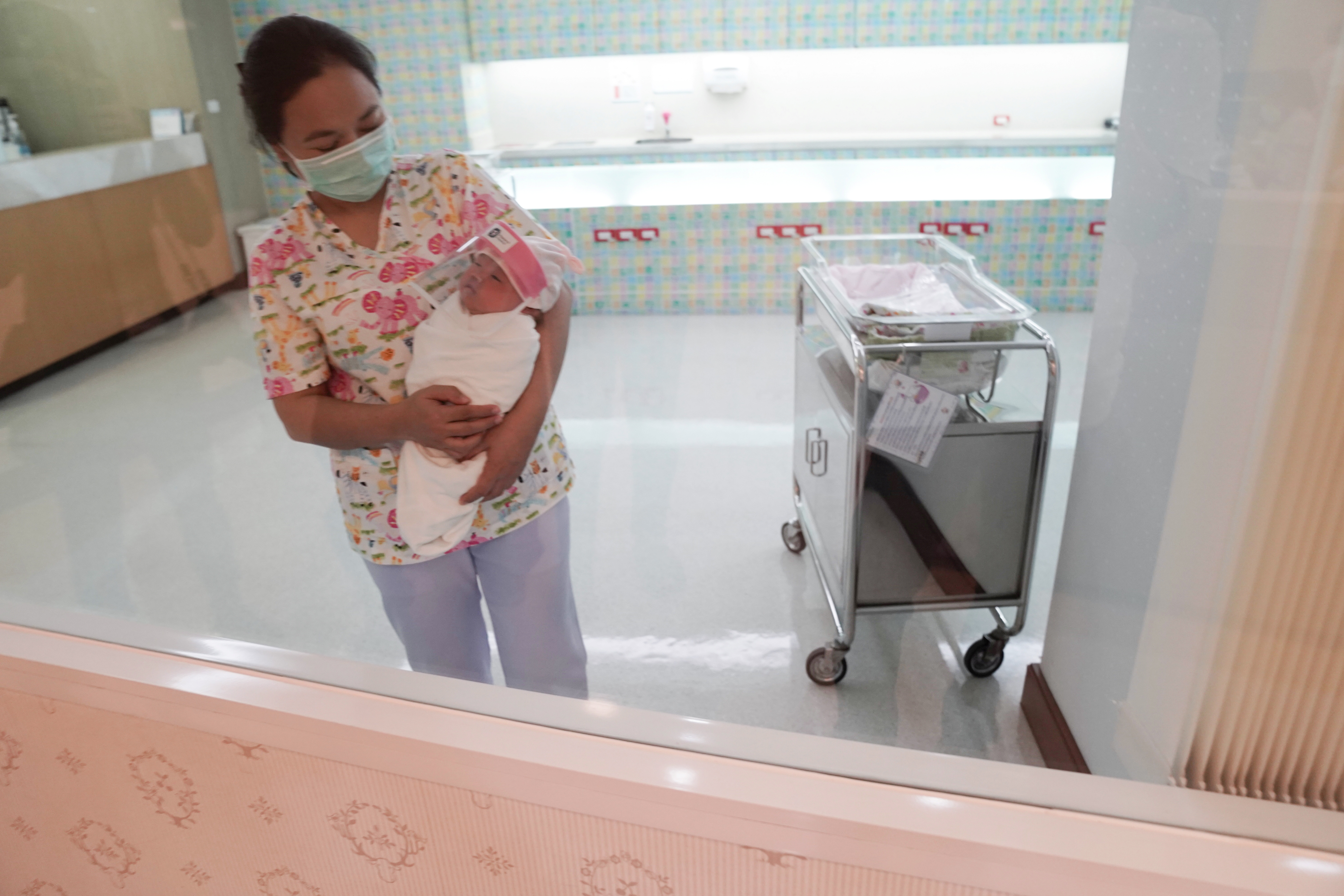 Una enfermera con una mascarilla protectora sostiene a un bebé recién nacido con un protector facial durante el brote de COVID-19 en el hospital Praram 9 en Bangkok, Tailandia, 9 de abril de 2020 (REUTERS/Athit Perawongmetha)