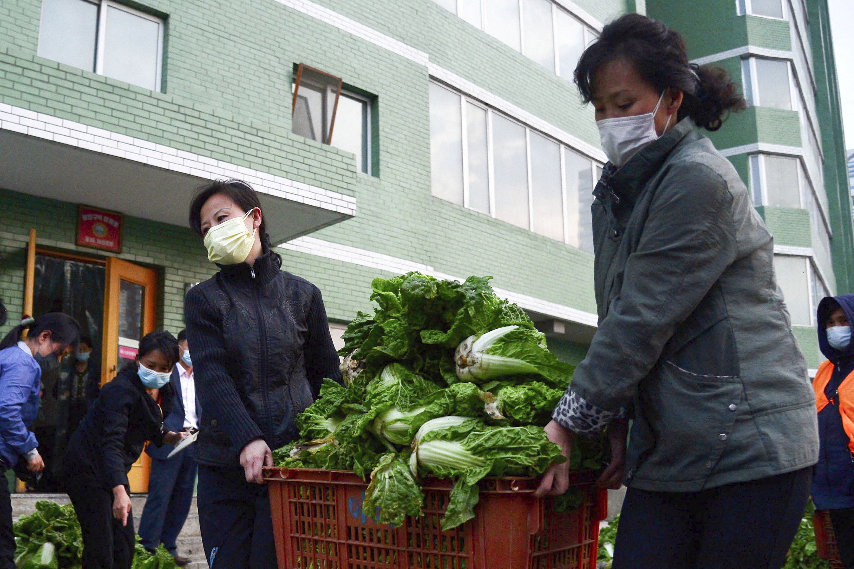 Residentes con mascarillas protectoras transportan verduras, en medio de los crecientes temores por la propagación de la enfermedad coronavirus (COVID-19), en Pyongyang, Corea del Norte, en esta foto tomada el 16 de mayo de 2022 y publicada por Kyodo el 17 de mayo de 2022. Obligatorio crédito Kyodo/a través de REUTERS 