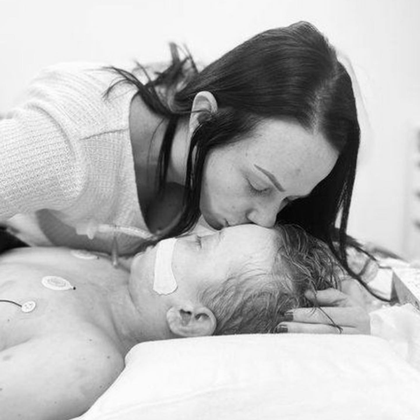 La madre besa a su hijo en la cama del hospital 