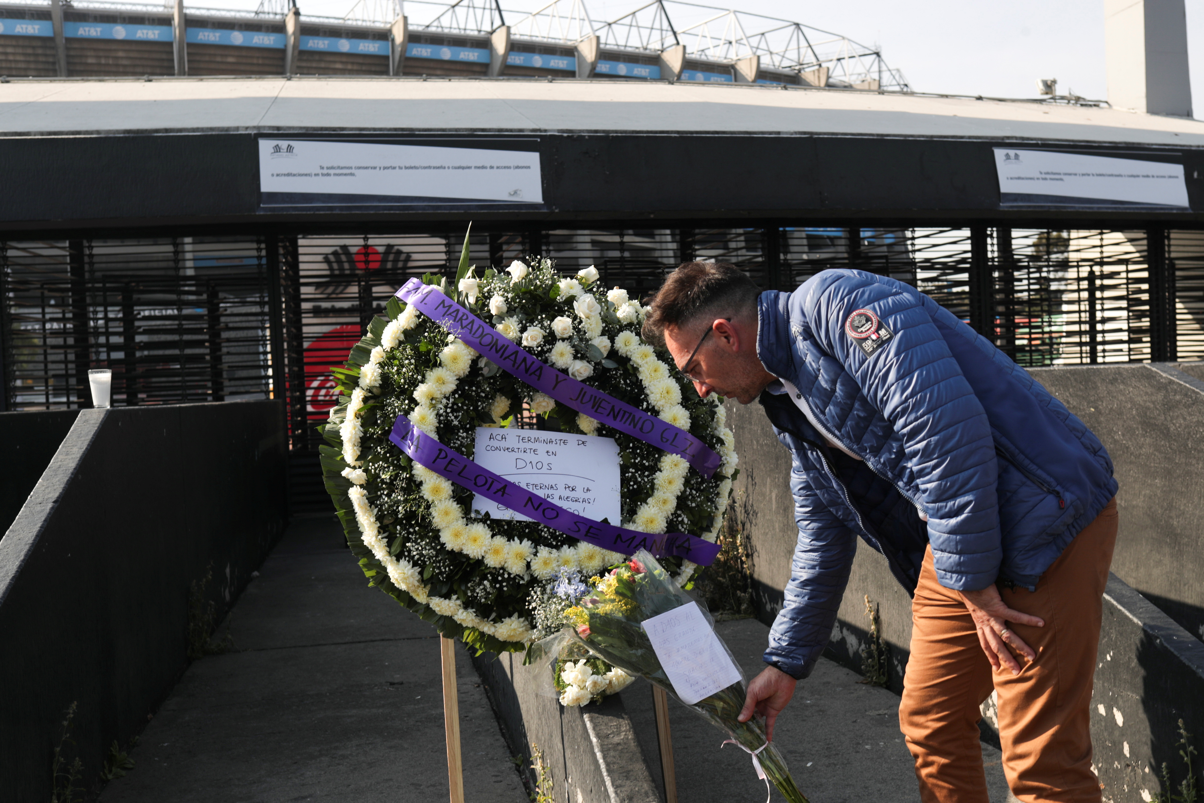Un fanático coloca flores junto a una ofrenda floral en memoria de Diego Armando Maradona afuera del estadio Azteca, en la Ciudad de México, México, 26 de noviembre de 2020.