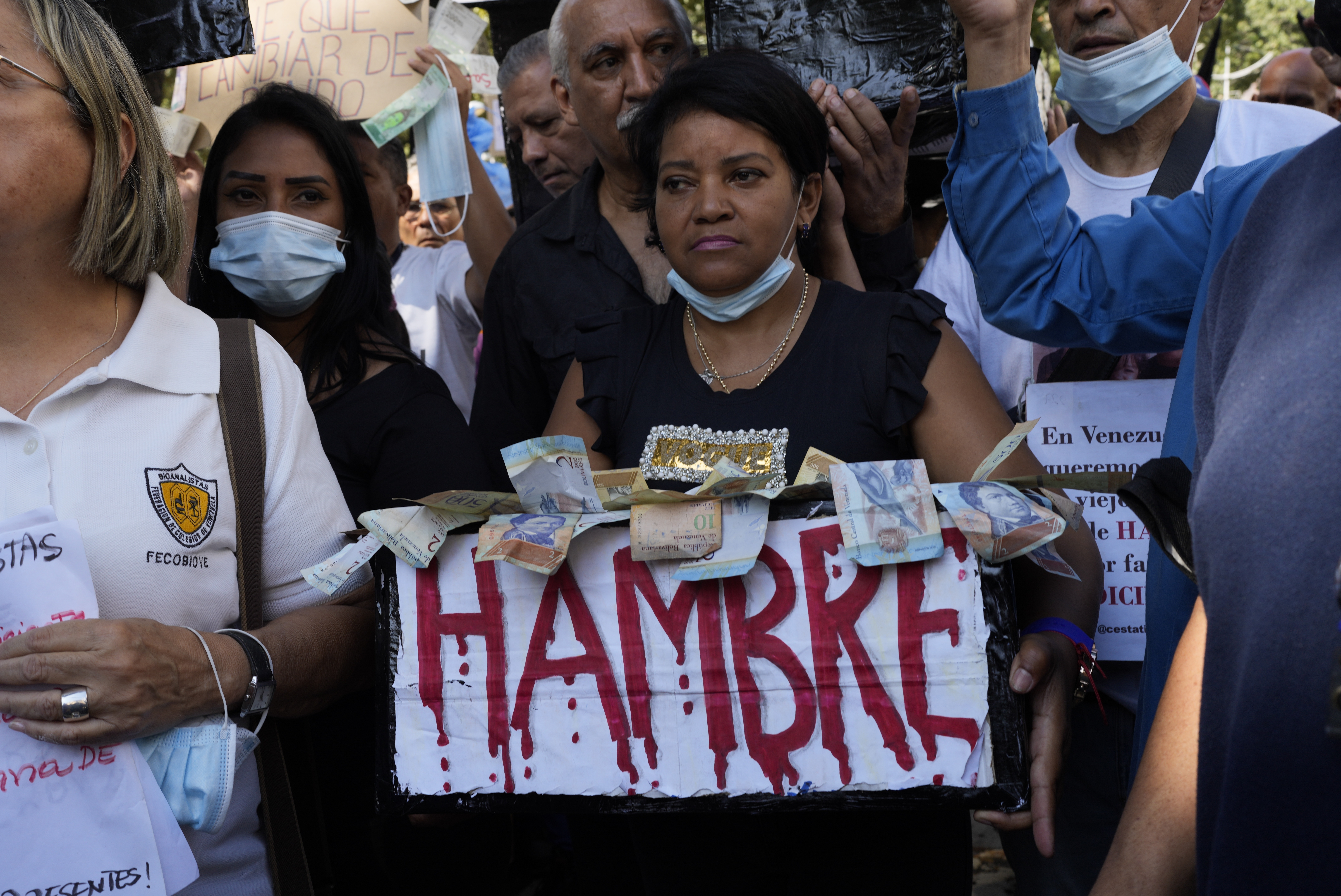 Un manifestante lleva una caja de billetes de bolívar que dice "hambre" durante una manifestación por mejores salarios y beneficios en Caracas, Venezuela, el miércoles 11 de enero de 2023. (AP Foto/Ariana Cubillos)