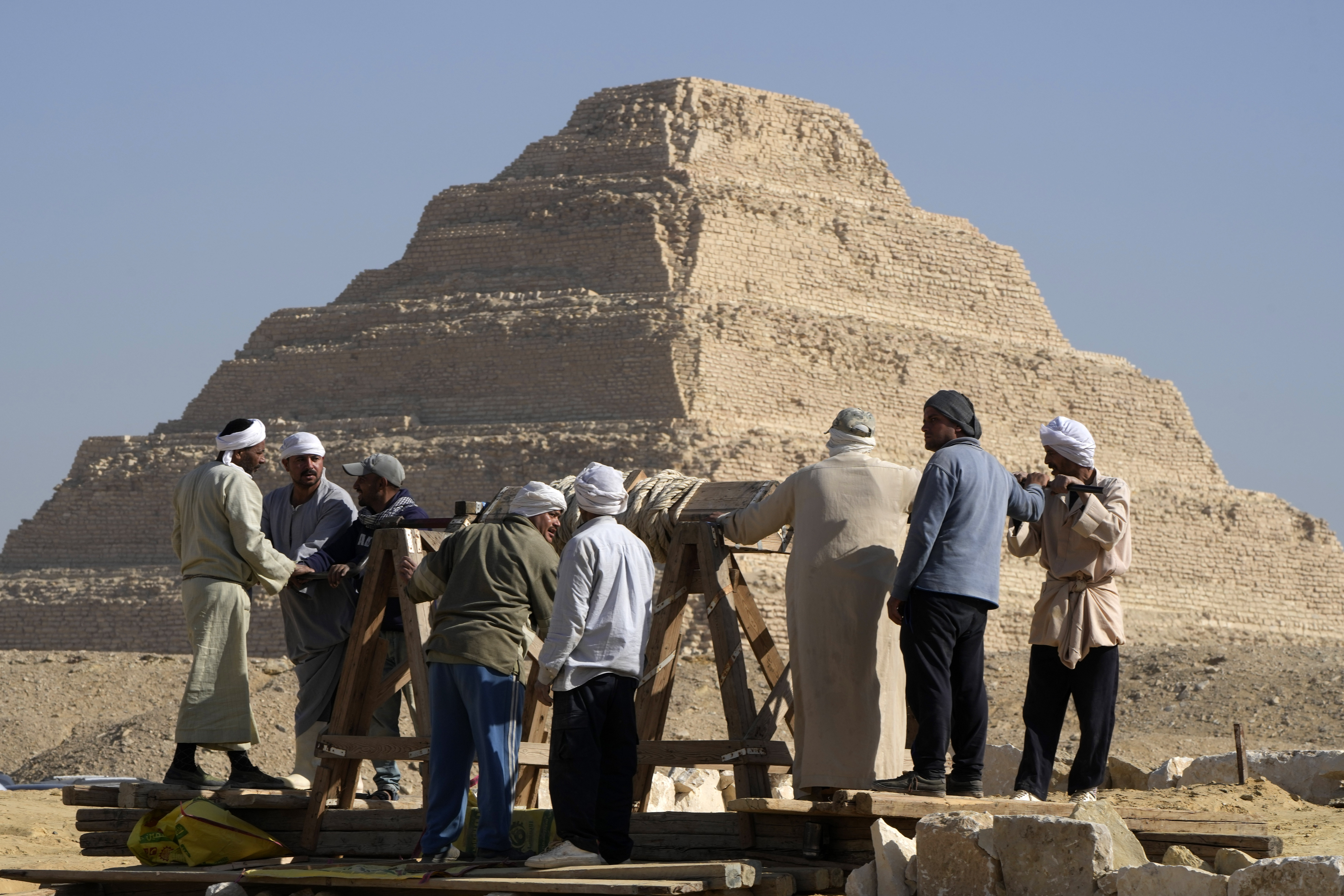 Los trabajadores utilizan una polea con baldes para sacar la arena que se encuentra dentro de las tumbas (Foto AP/Amr Nabil)