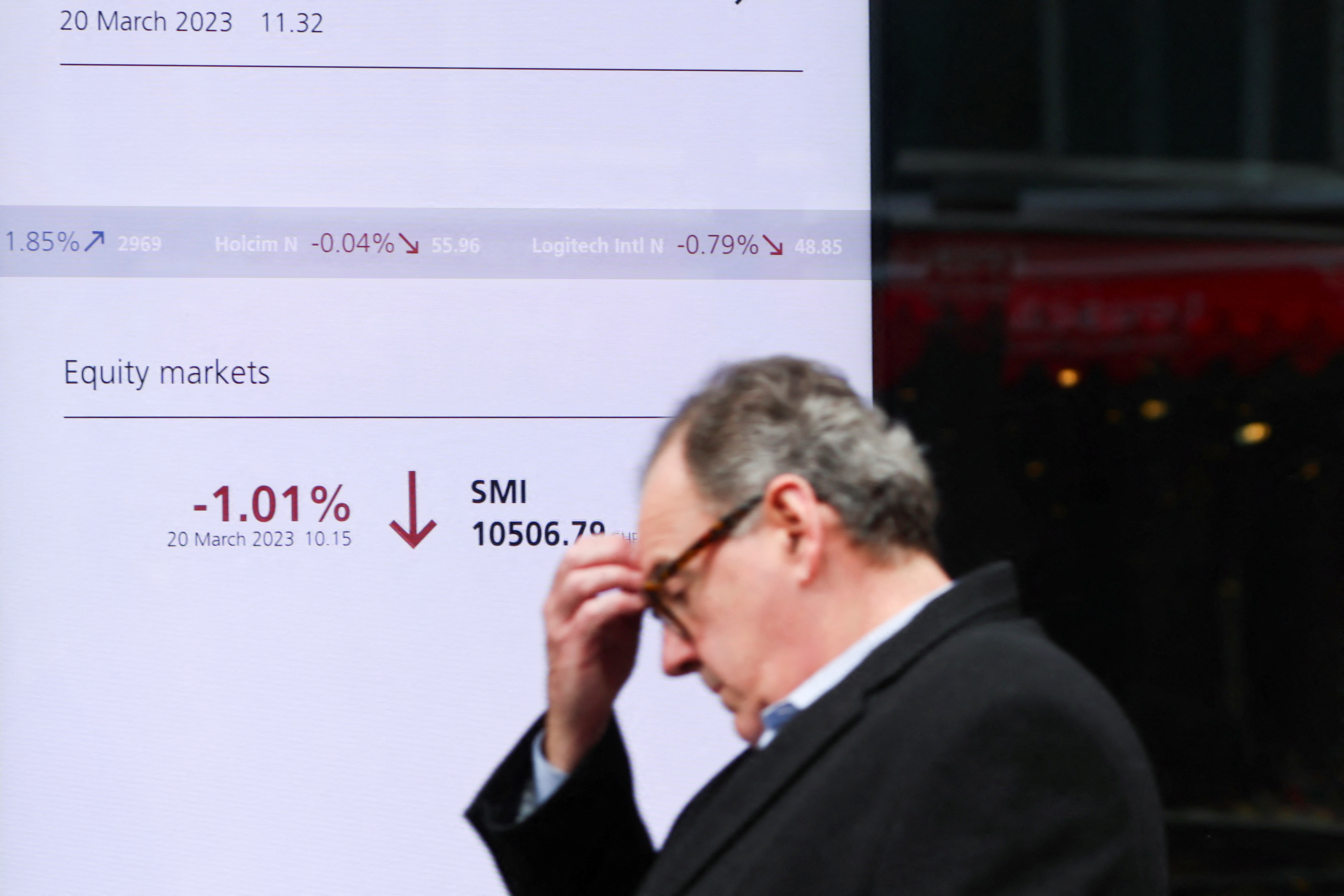 Una persona camina delante de una pantalla que muestra el índice del mercado suizo (SMI) en un banco suizo UBS en Zurich, Suiza 20 de marzo 2023 (Reuters)
