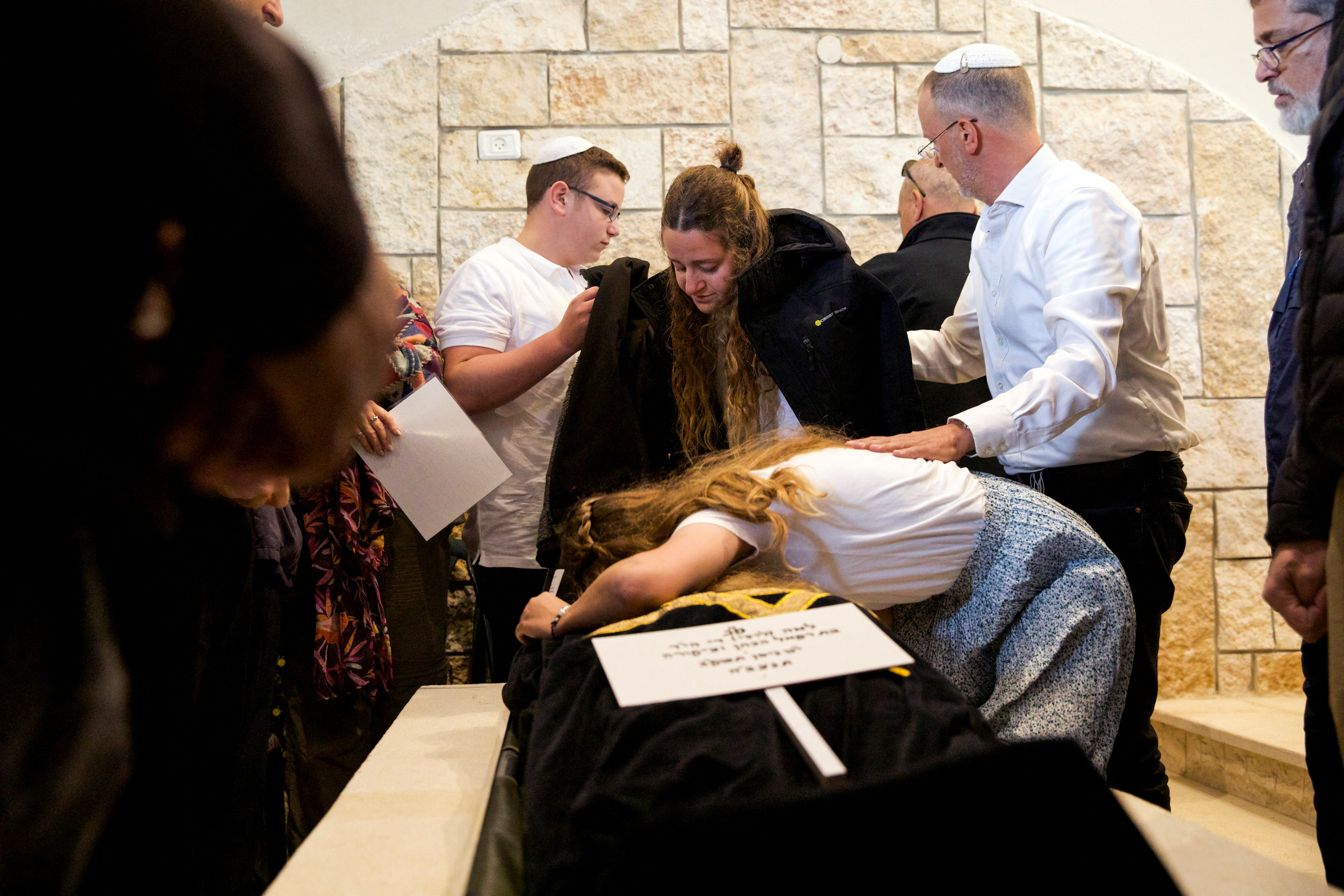 El marido y los hijos de Lucy Dee, la madre de las hermanas británico-israelíes Maia y Rina Dee que murieron en un ataque a tiros cuando la familia conducía su coche, se abrazan a su cuerpo en su funeral en Kfar Etzion, en Cisjordania, 11 de abril de 2023. REUTERS/Shir Torem/Archivo