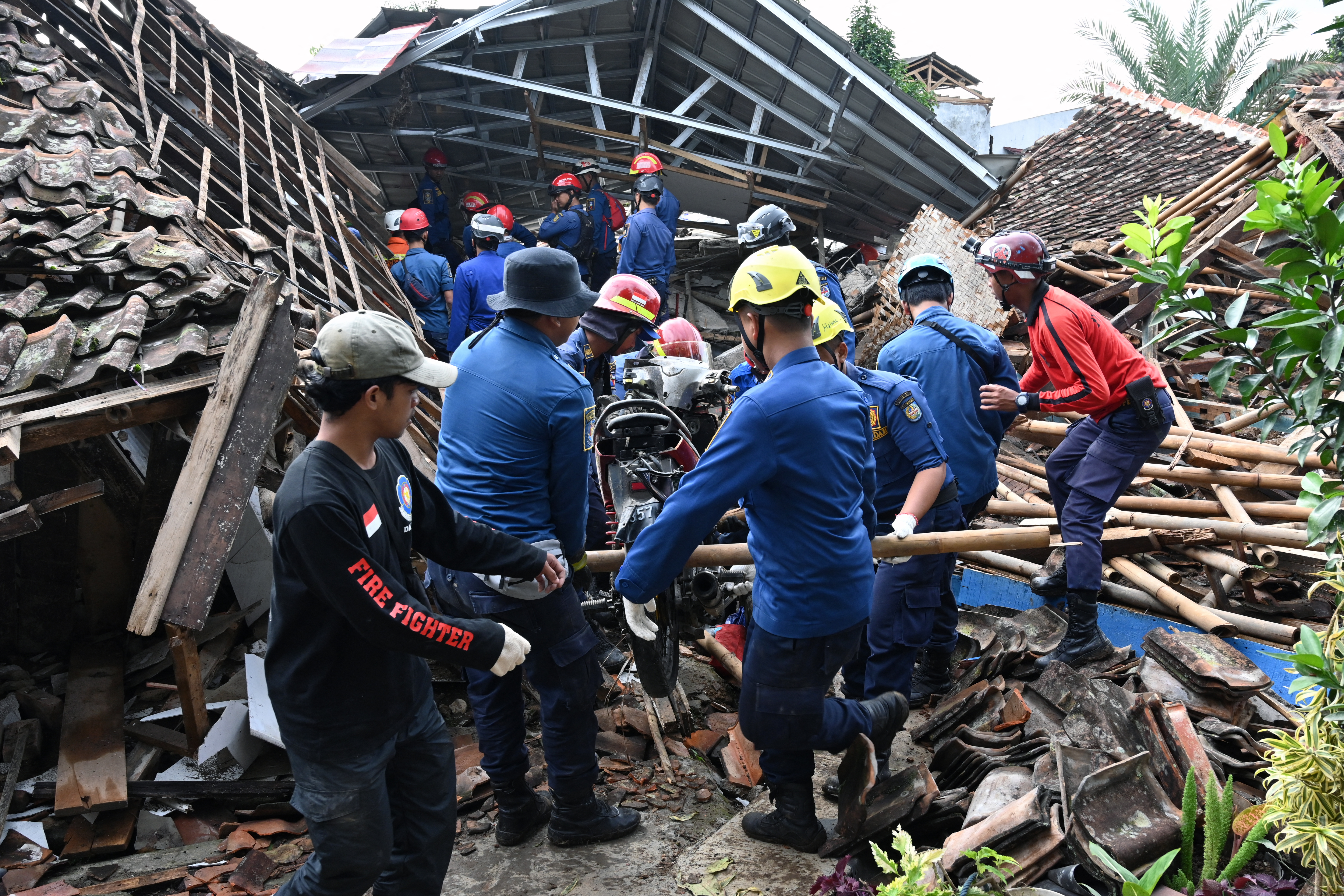 El personal de rescate retira una motocicleta mientras trabajan para encontrar a una niña desaparecida que se cree que está atrapada entre los escombros de una casa derrumbada en Cugenang en Cianjur (ADEK BERRY / AFP)