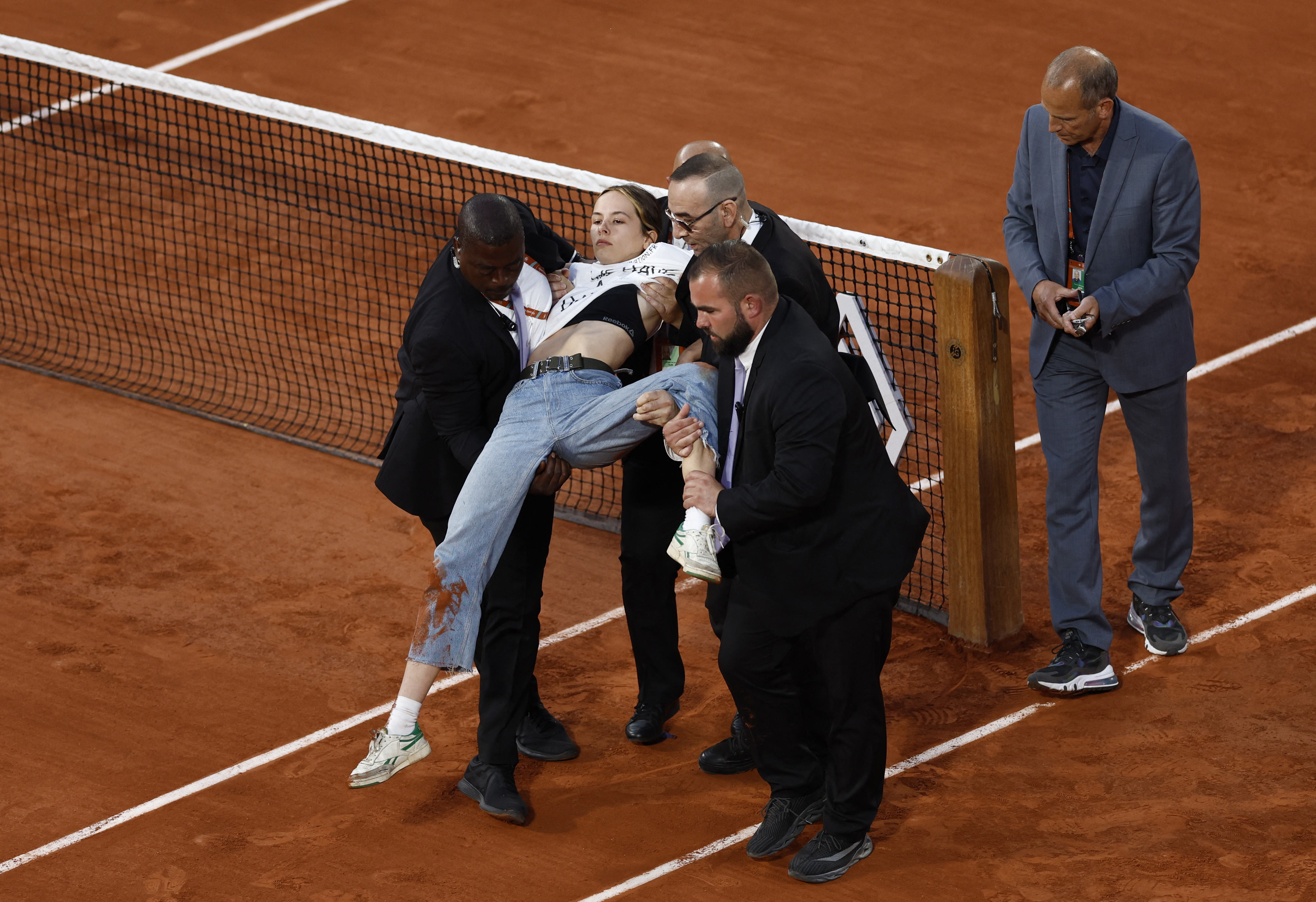 Los agentes de seguridad retiraron de la cancha a la joven activista que interrumpió la segunda semifinal de Roland Garros (Foto: REUTERS)
