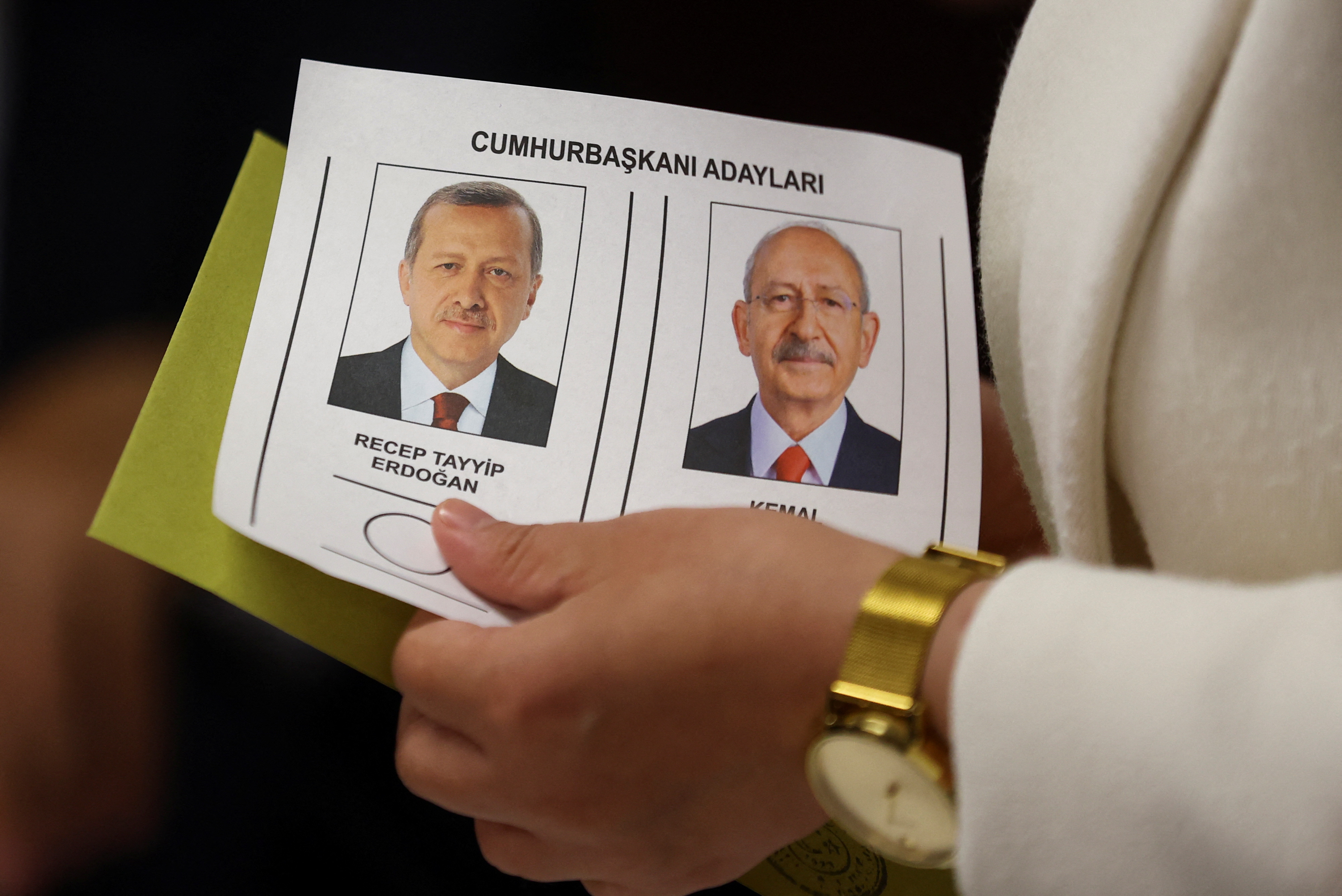 A person holds a ballot with pictures of Turkish President Tayyip Erdogan and presidential candidate of Turkey's main opposition alliance Kemal Kilicdaroglu at a polling station during the second round of the presidential election in Istanbul, Turkey May 28, 2023. REUTERS/Hannah McKay