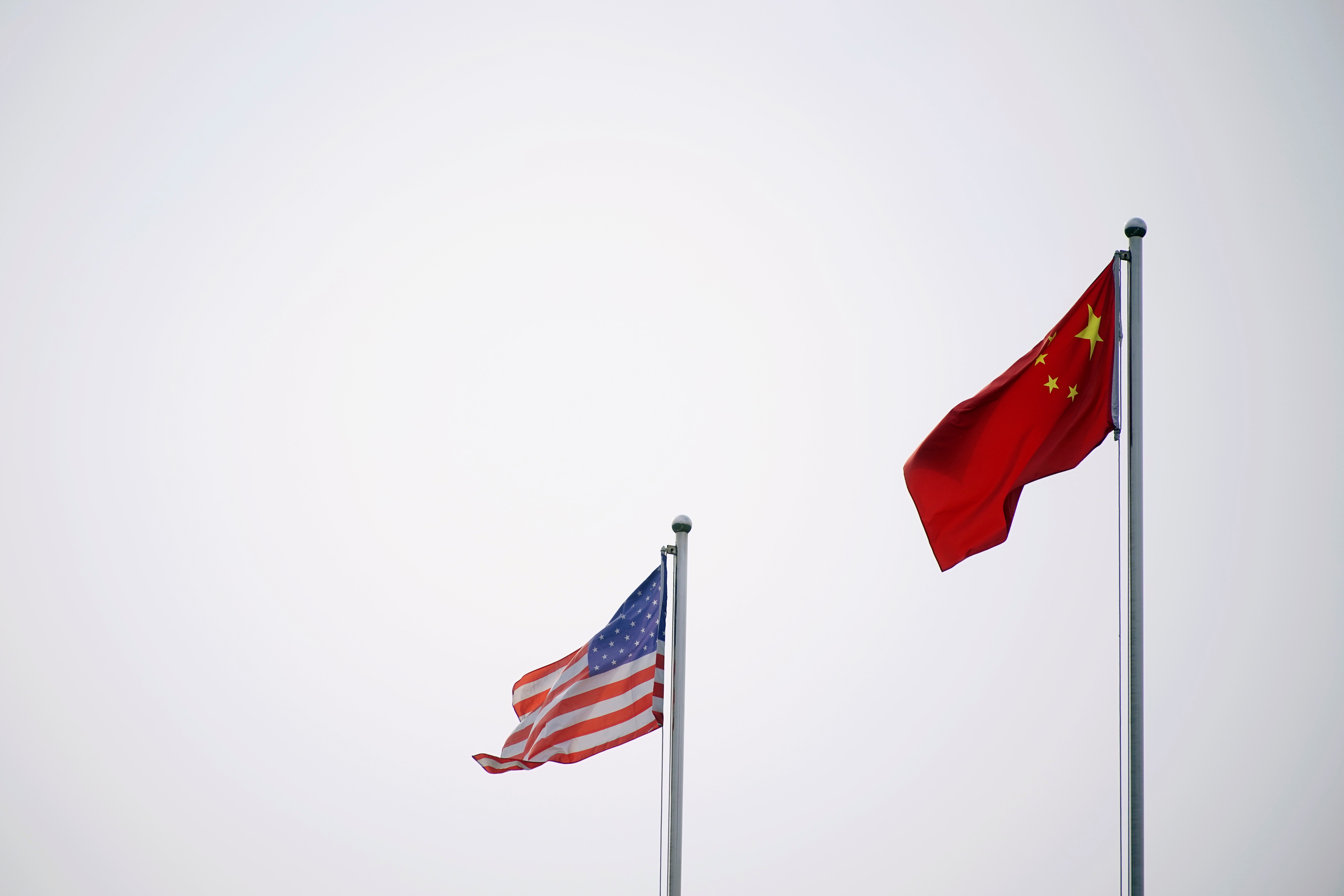 Chinese and U.S. flags flutter outside a company building in Shanghai, China April 14, 2021. REUTERS/Aly Song