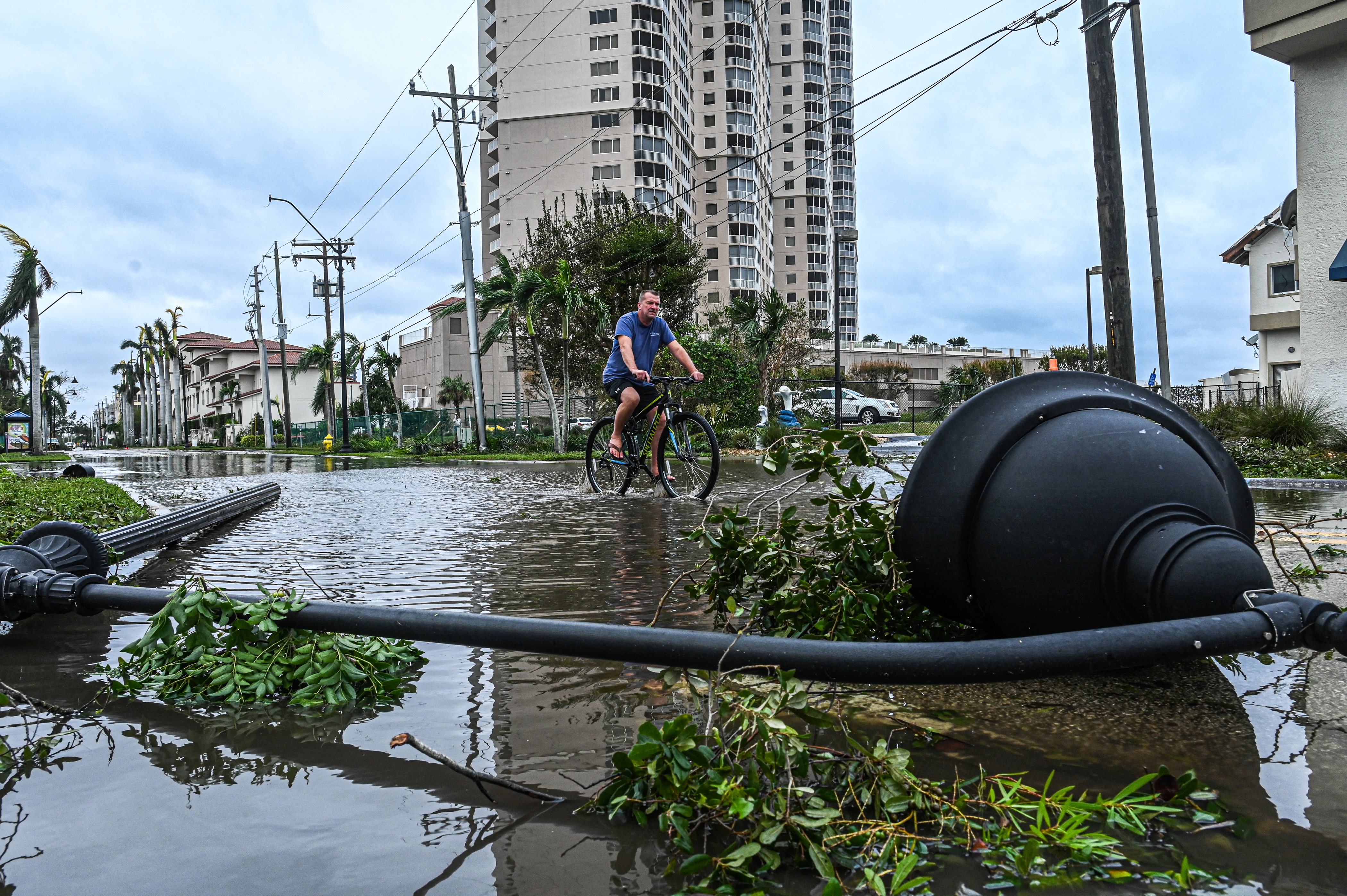 Un hombre pasa una farola caída mientras anda en bicicleta por el agua después del huracán Ian en Fort Myers, Florida, el 29 de septiembre de 2022. (Giorgio VIERA / AFP)