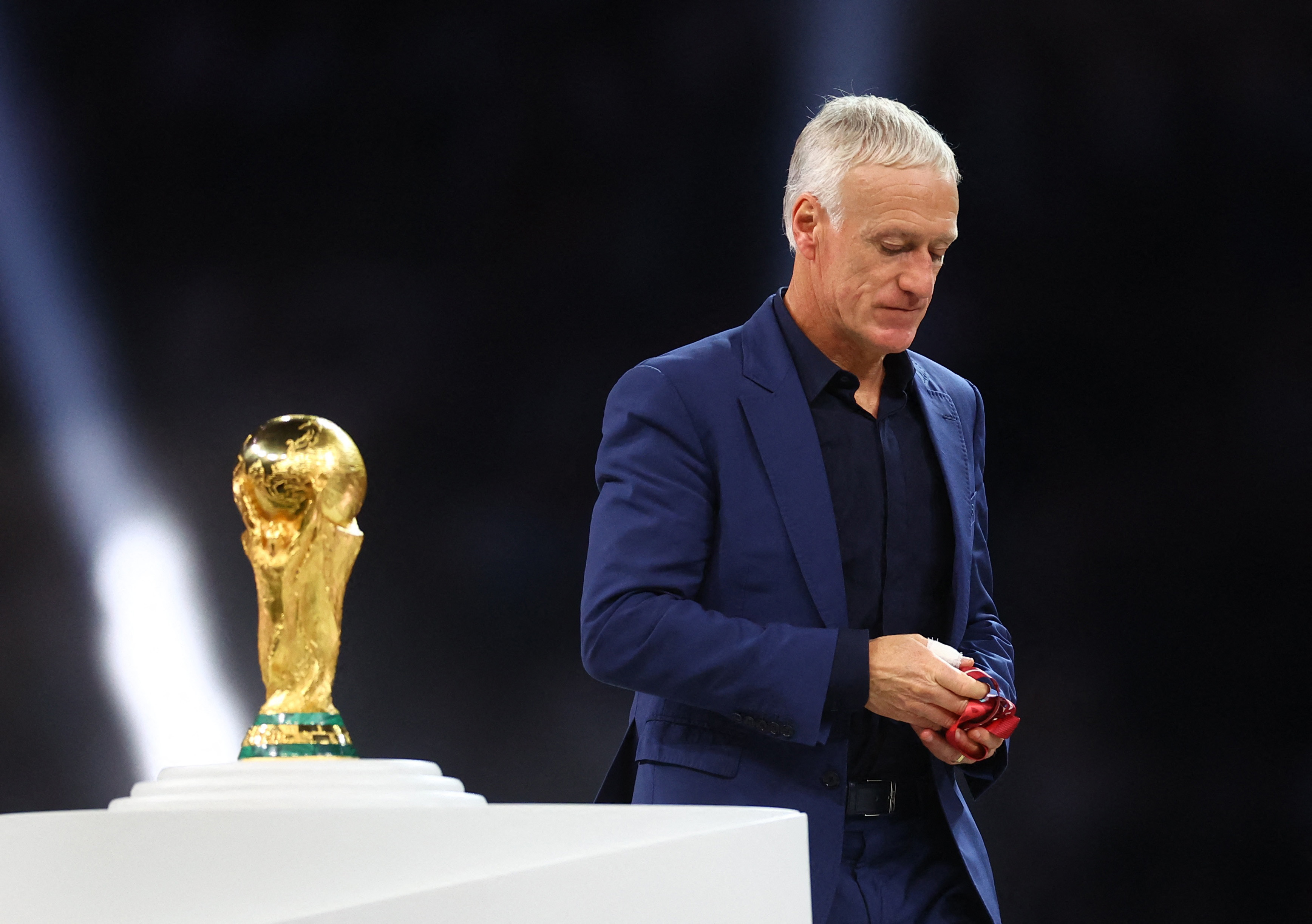 Soccer Football - FIFA World Cup Qatar 2022 - Final - Argentina v France - Lusail Stadium, Lusail, Qatar - December 18, 2022 France coach Didier Deschamps looks dejected as he walks past the World Cup trophy during the ceremony after the match REUTERS/Kai Pfaffenbach