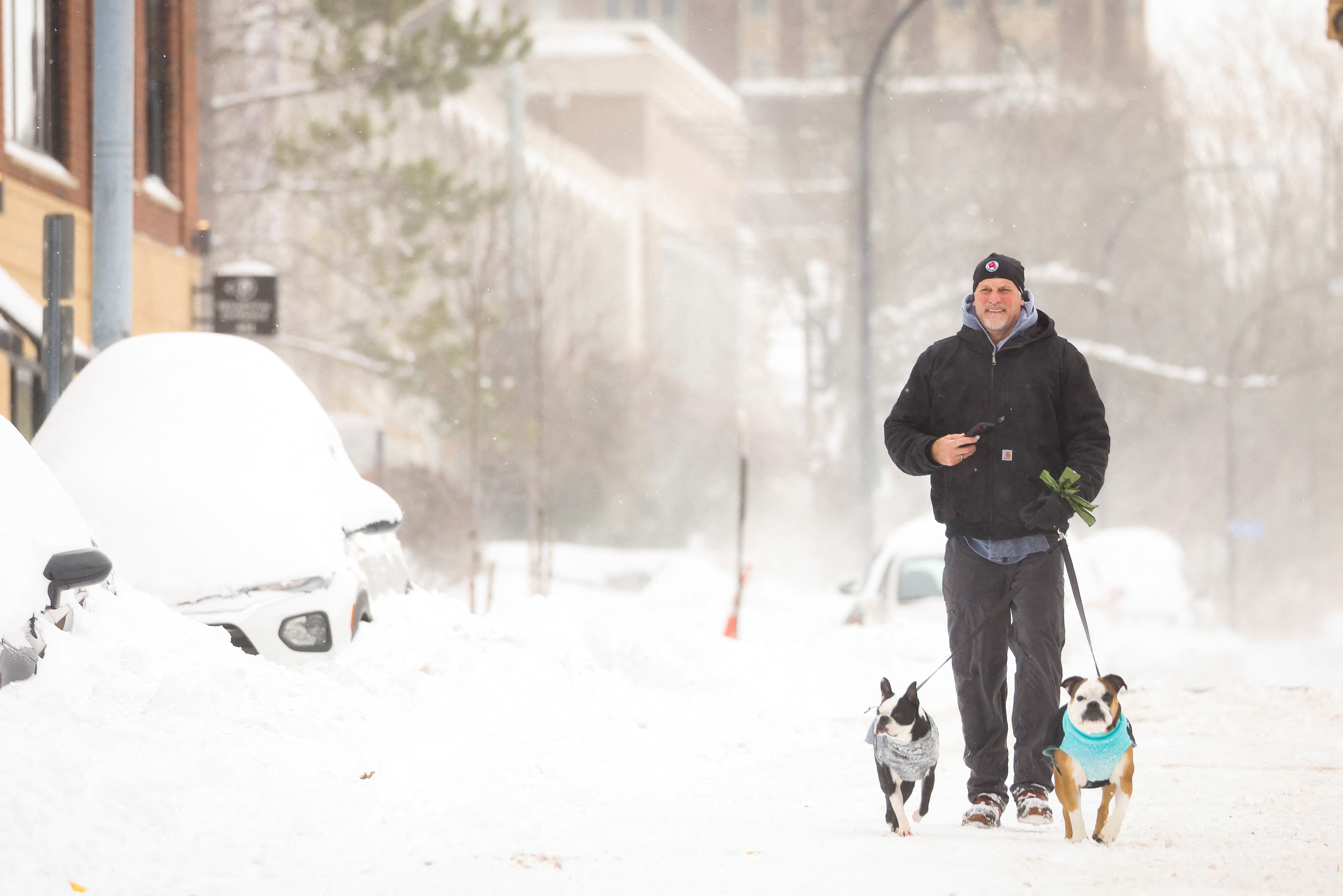 Un uomo porta a spasso i suoi cani per strada mentre il rigido clima invernale colpisce Buffalo, New York
