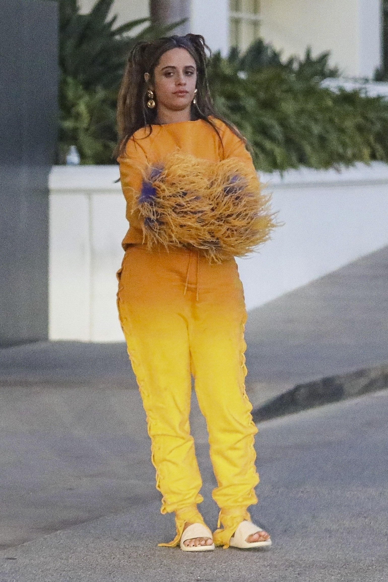 Camila Cabello sorprendió con su look para ir a comer a un exclusivo restaurante en Santa Mónica con un grupo de amigos. La artista lució un conjunto de pantalón y buzo naranja y amarillo, con plumas en las mangas. Además, llevó sandalias de goma