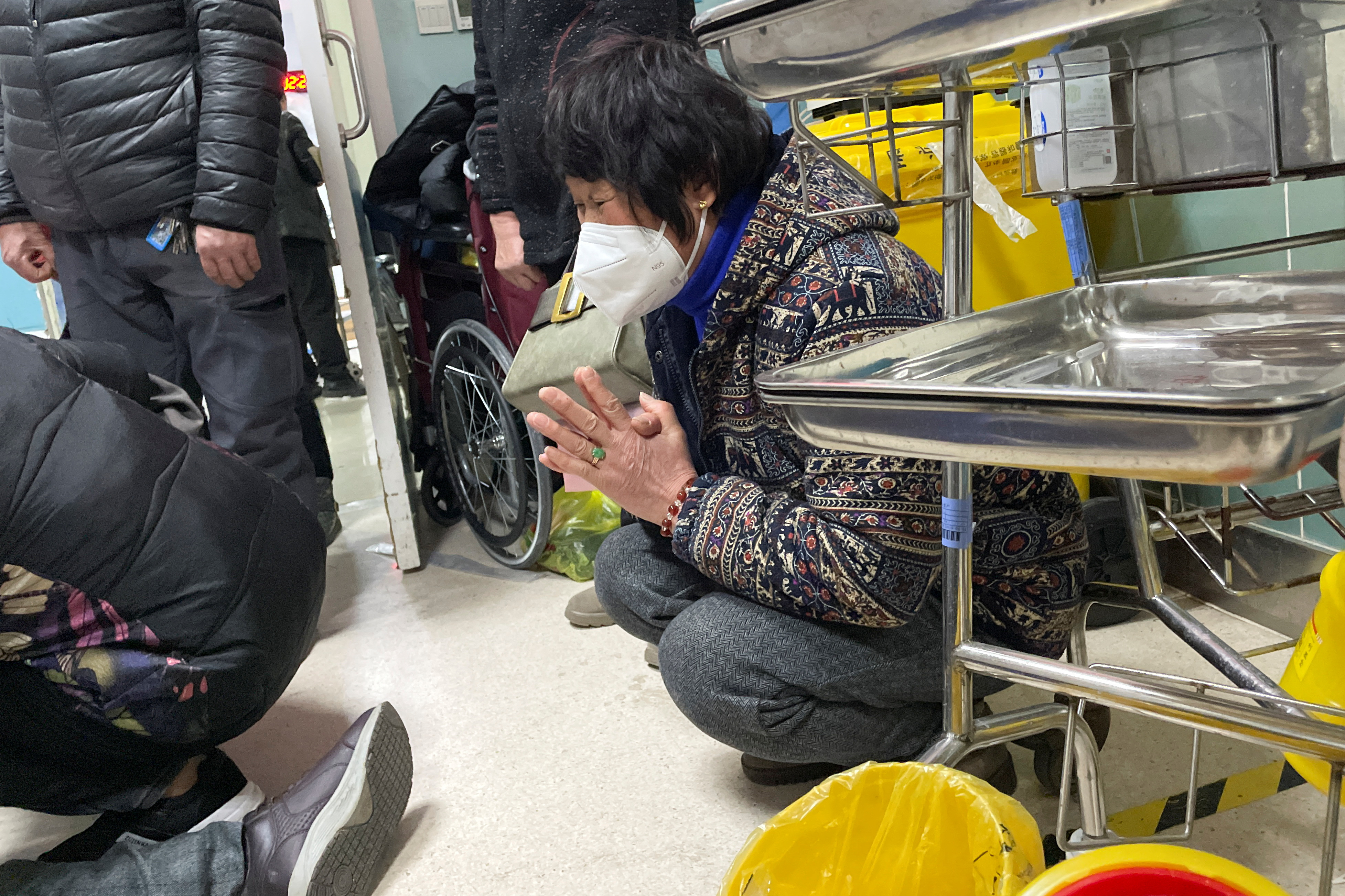 Un pariente reza junto a un hombre que recibe compresiones torácicas a través de un dispositivo de RCP mientras está acostado en el piso en el departamento de emergencias de un hospital, en medio del brote de la enfermedad por coronavirus (COVID-19) en China