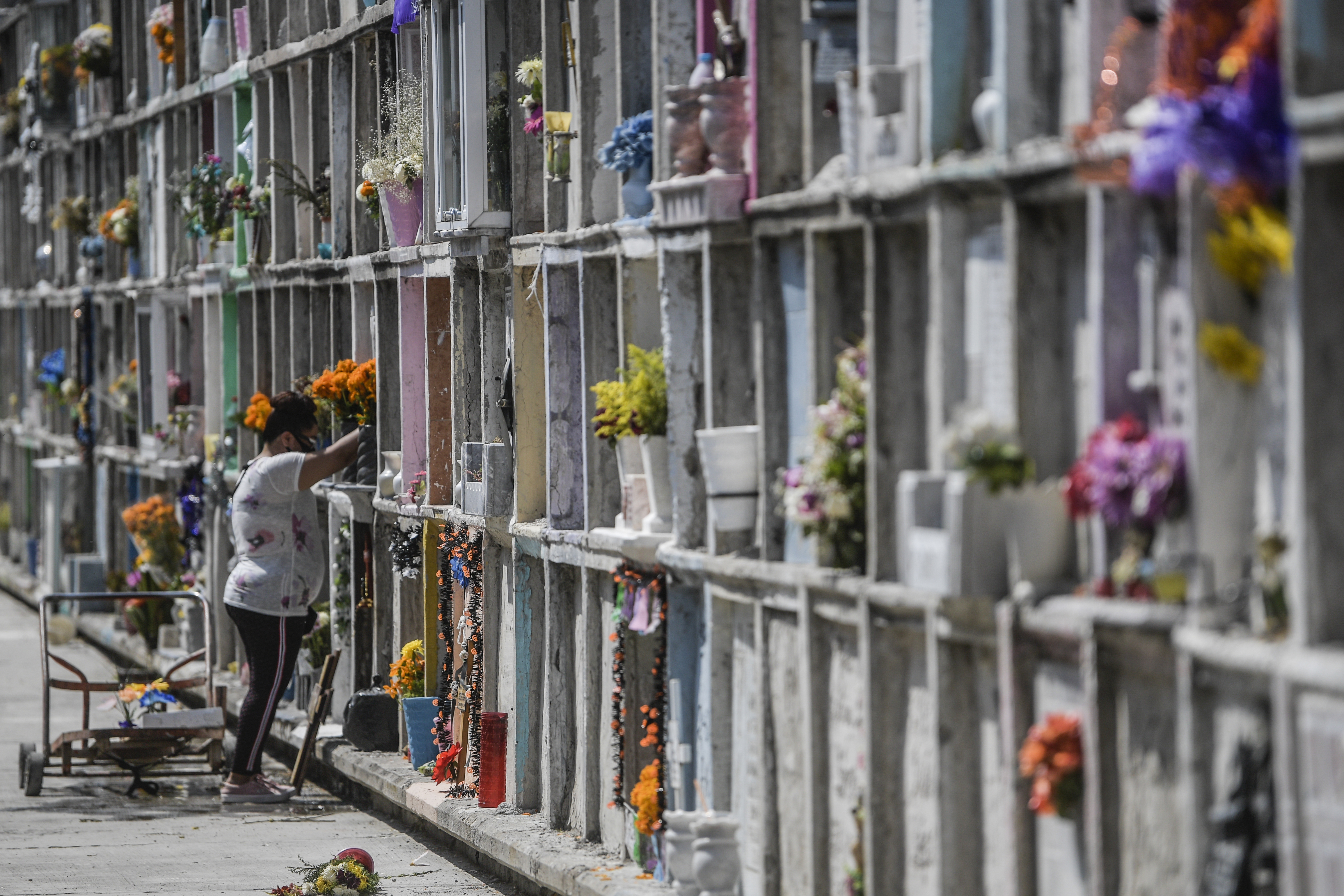 Una mujer decora la tumba de un familiar antes del Día de Muertos en el panteón municipal de Nezahualcóyotl, México, el 28 de octubre de 2020, en medio de la pandemia del coronavirus COVID-19.